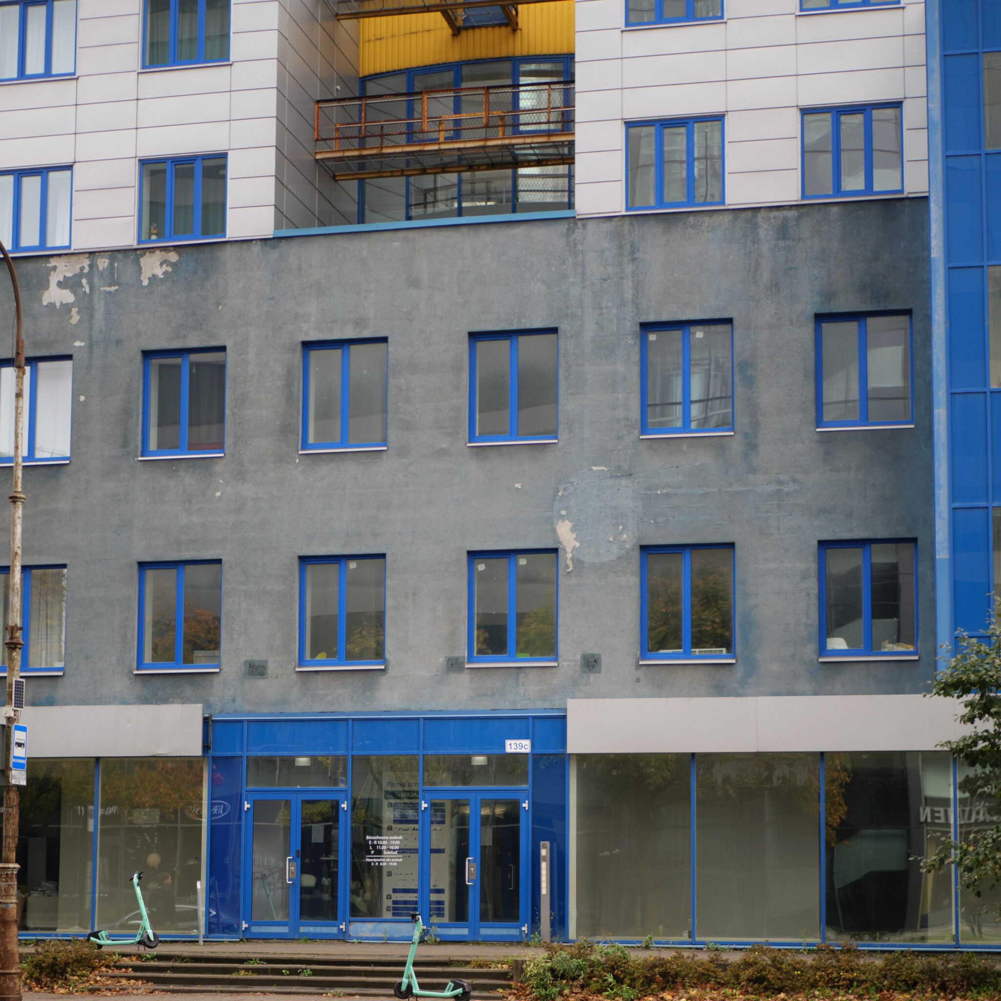 Mitmekorruseline hoone siniste akende ja uksega.