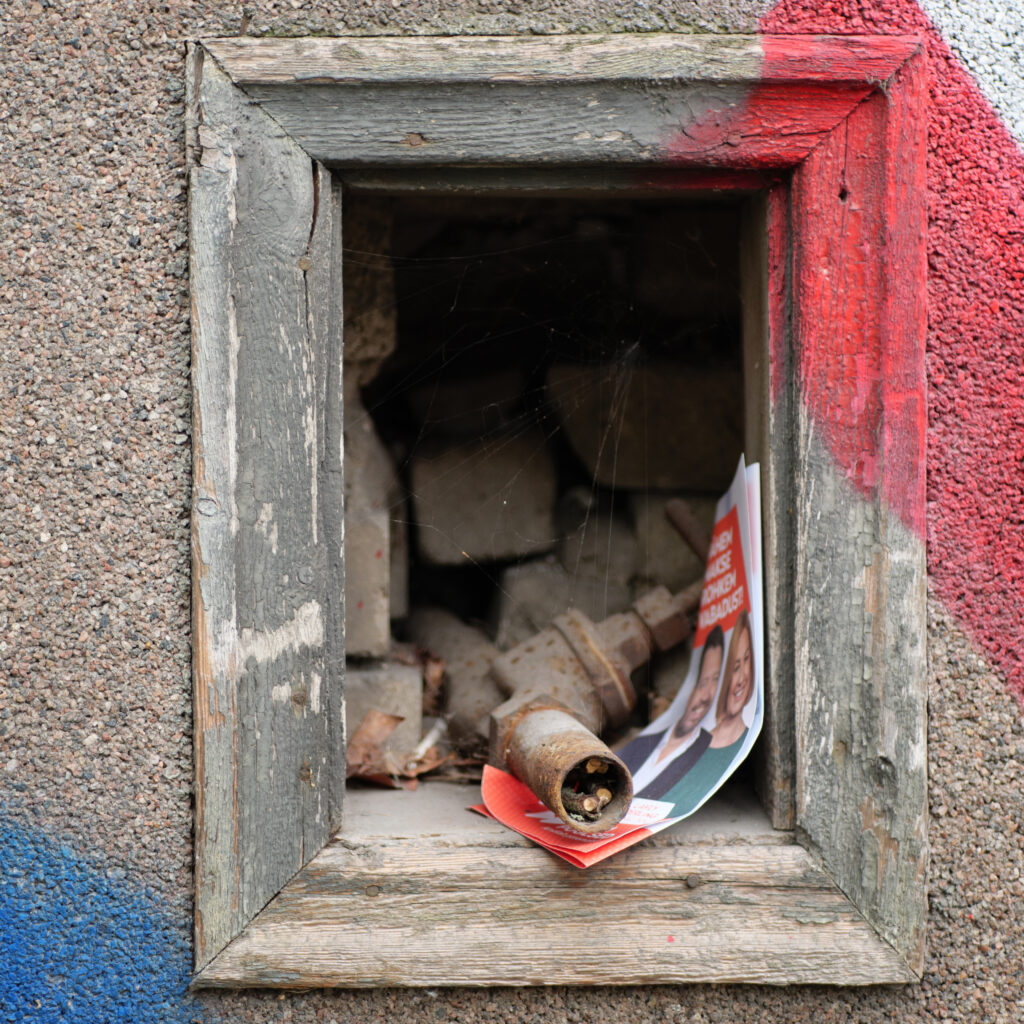 Aken roostes eseme ja plakatiga sees.