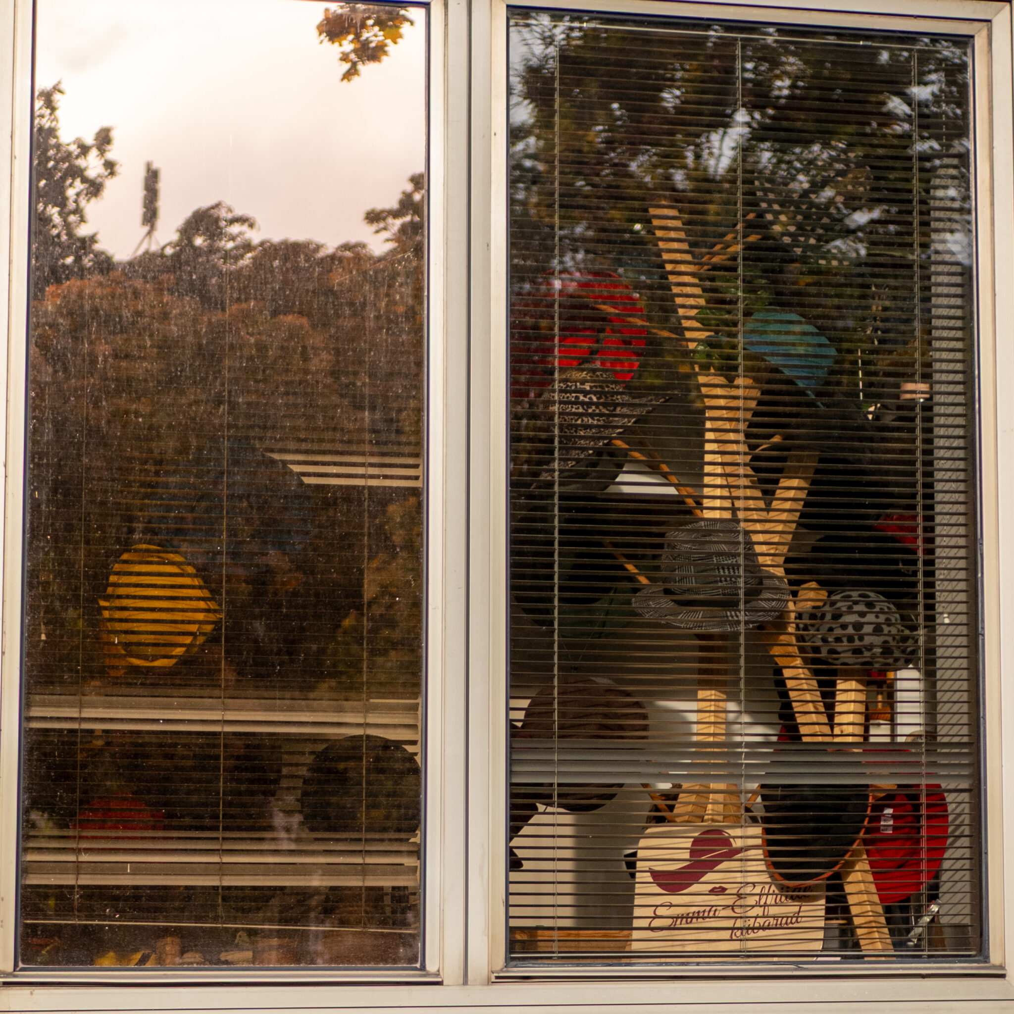 Akna taga mütsid ja kotid, aknast peegeldub loodus ja hoone.