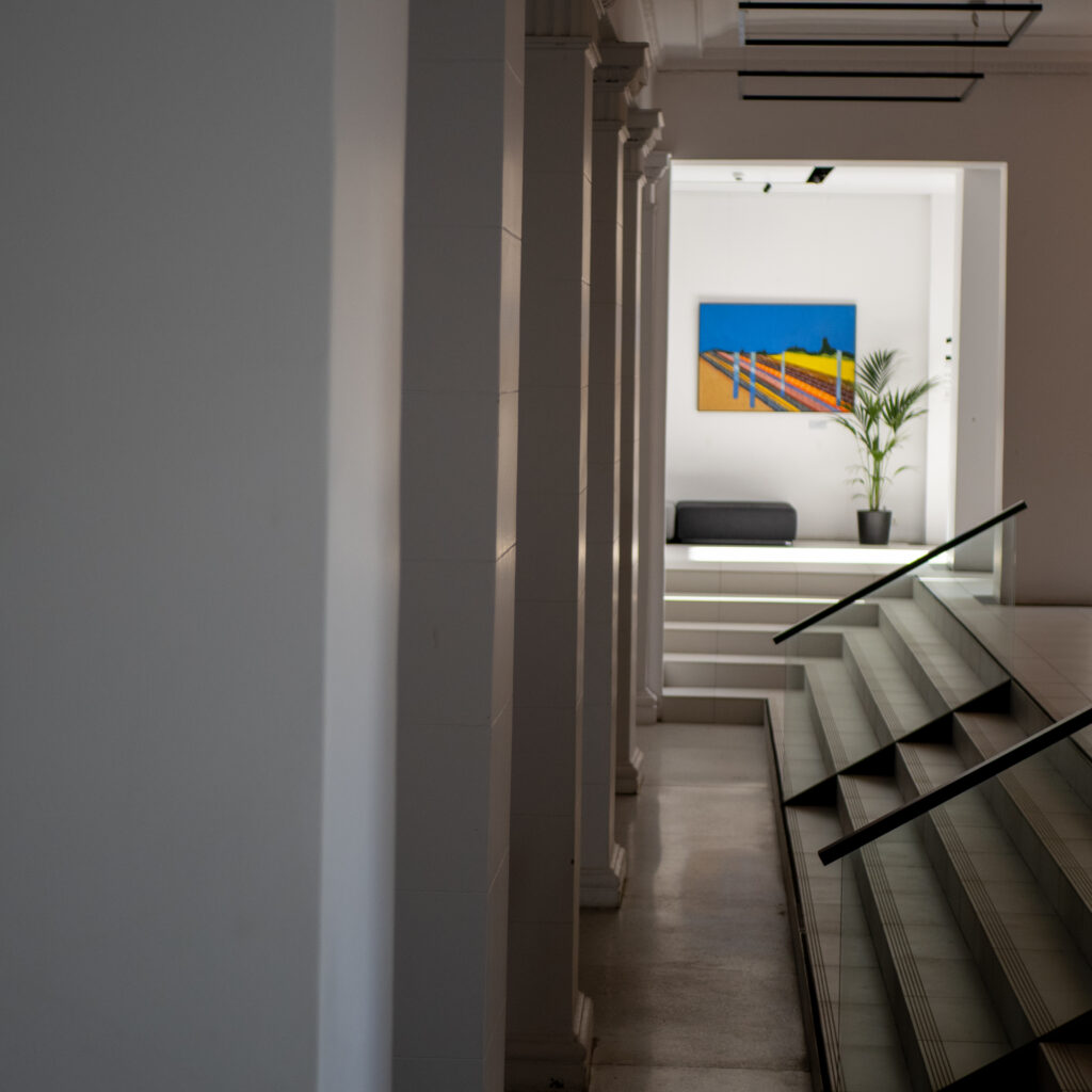 Klaaspiirdega trepp viib ruumi, kus on värvikas maal.