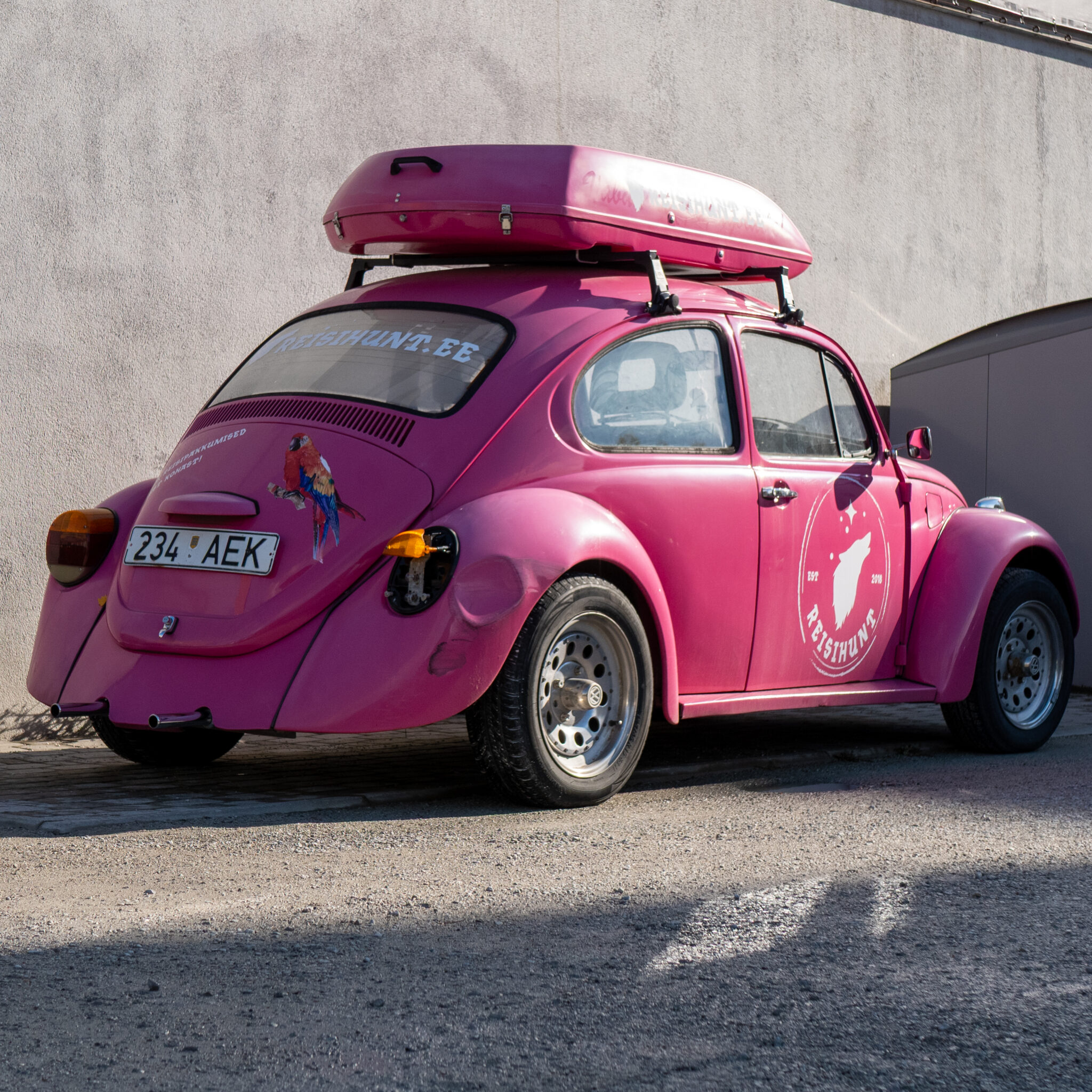 Roosa Volkswagen Beetle katusele kinnitatud pagasiga.