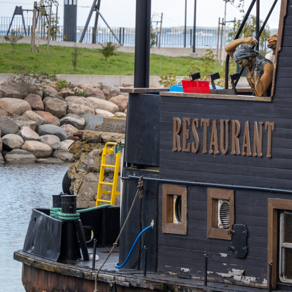 Mereröövliteemaline restoranilaev dokis kivise ranniku ääres.
