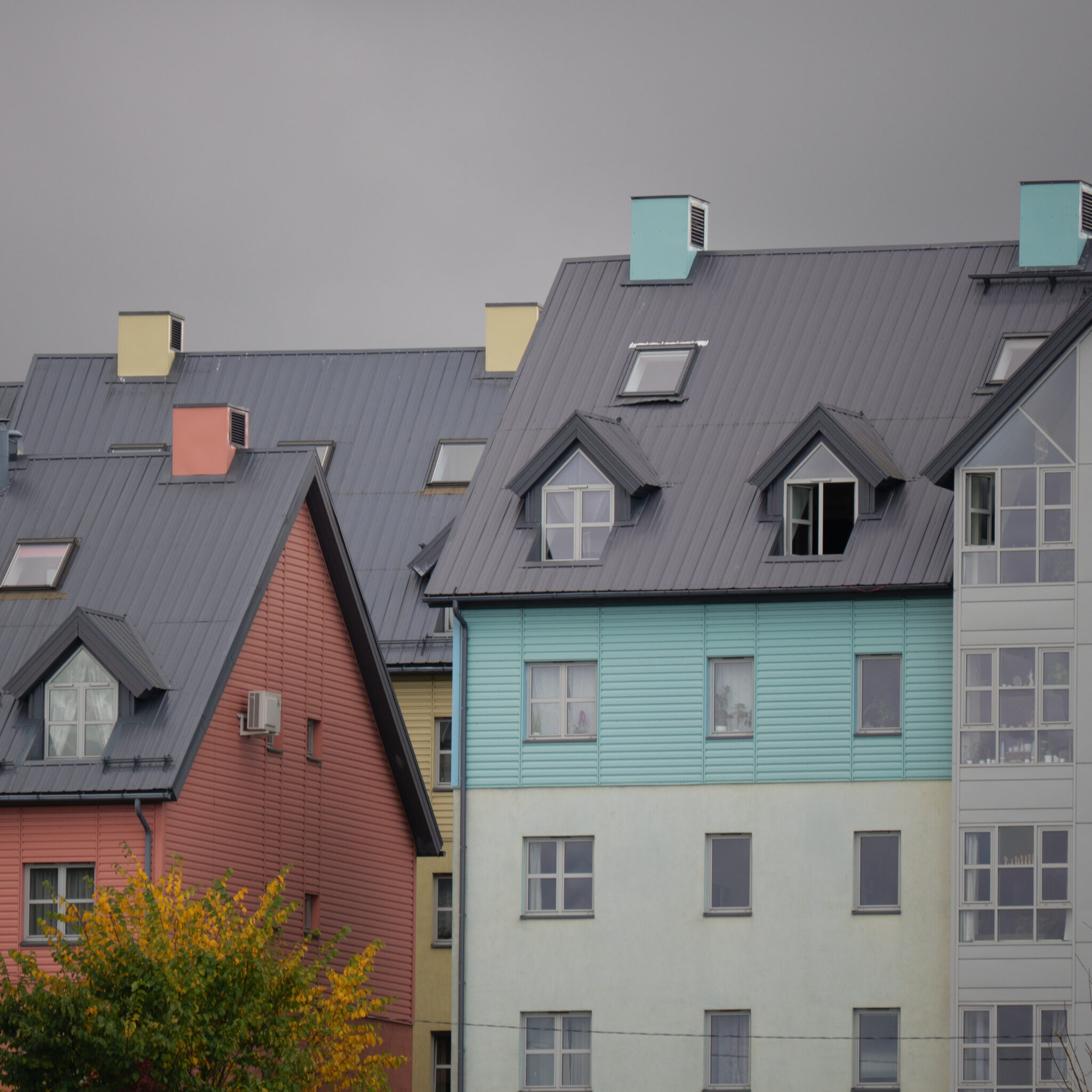 Rida värvilisi mitmekorruselisi maju hallide katustega.