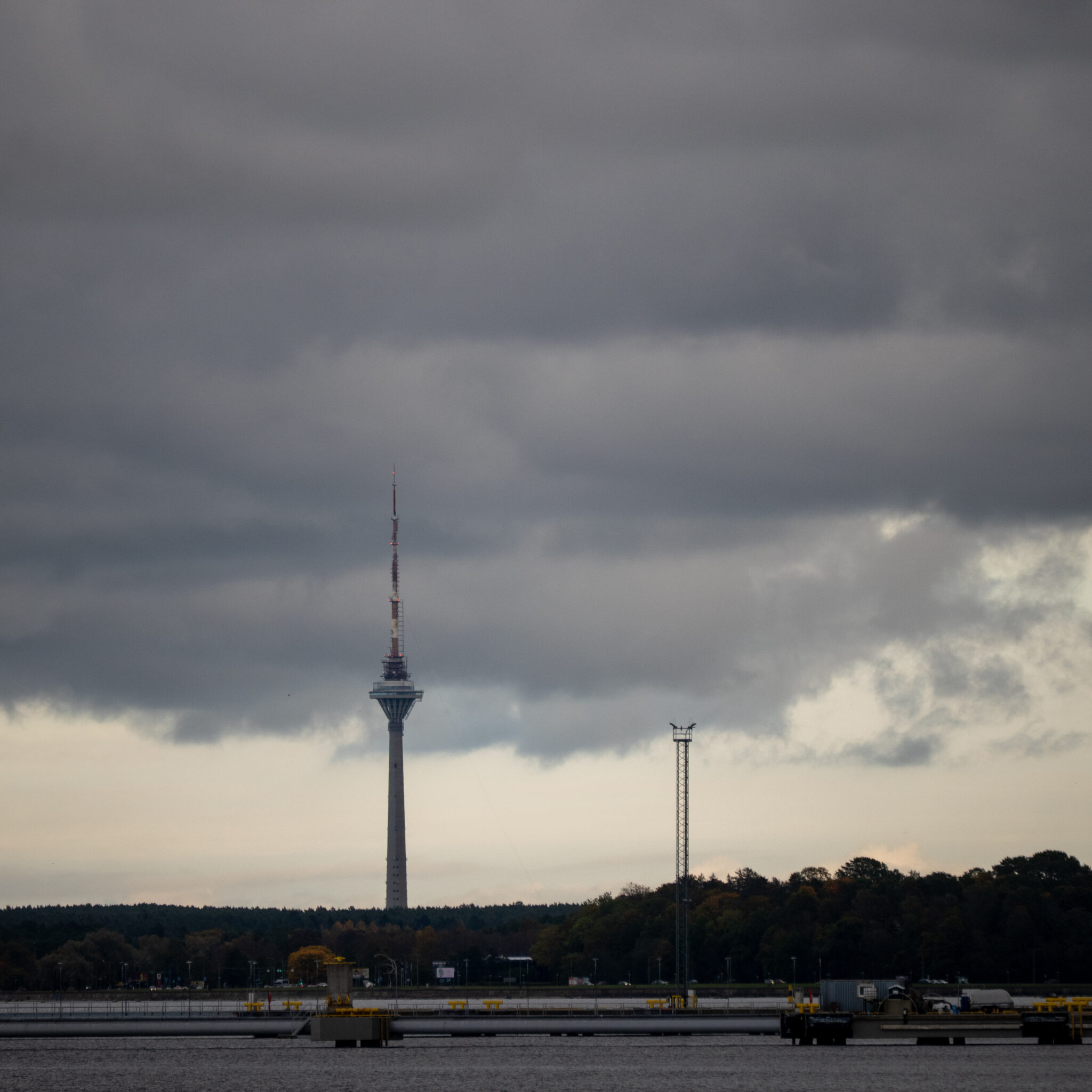 Kõrge torn pilvise taeva ja metsase taustaga.