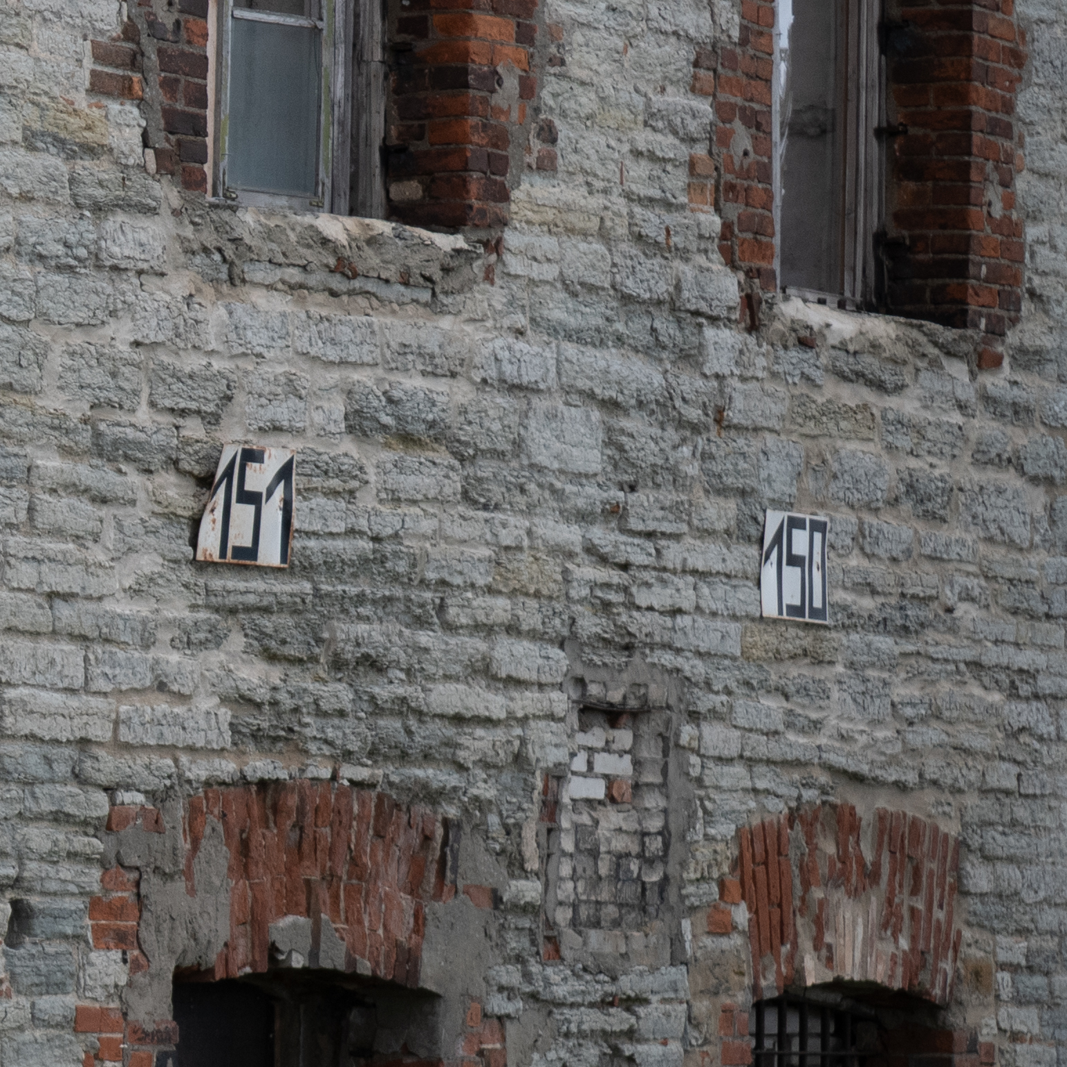 Kaks numbrimärgiga silti vanal tellisseinal.