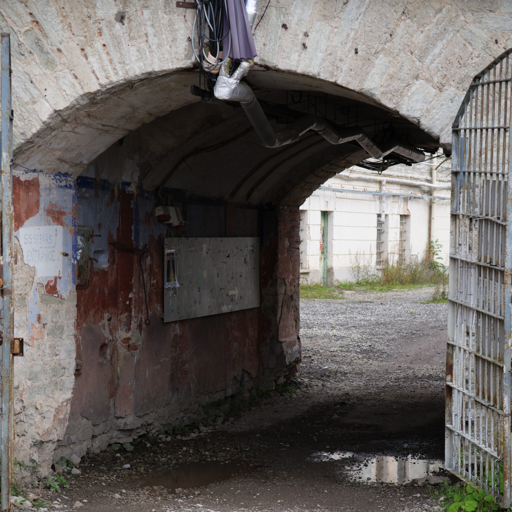 Vana lagunenud tunneli sissepääs roostes metallväravatega.