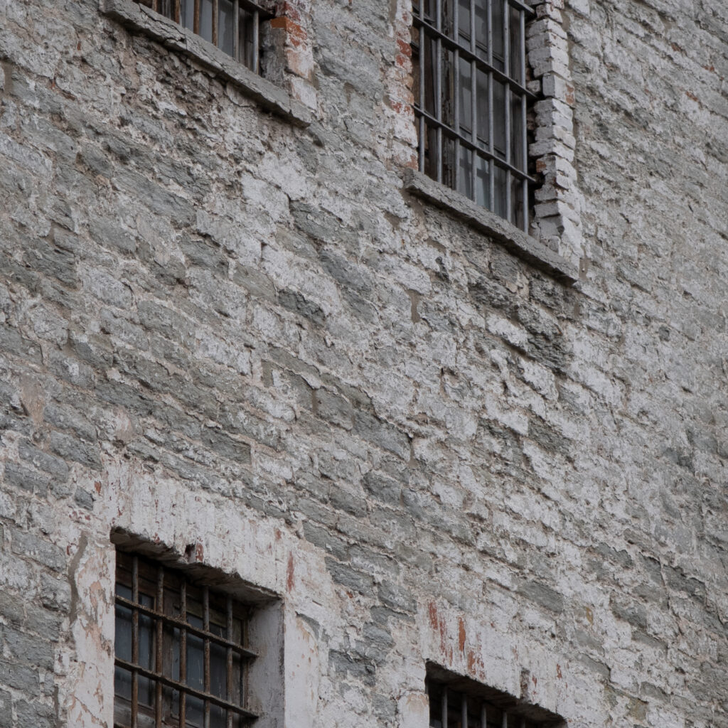 Vana ilmastikust kulunud tellishoone trellitatud akendega.