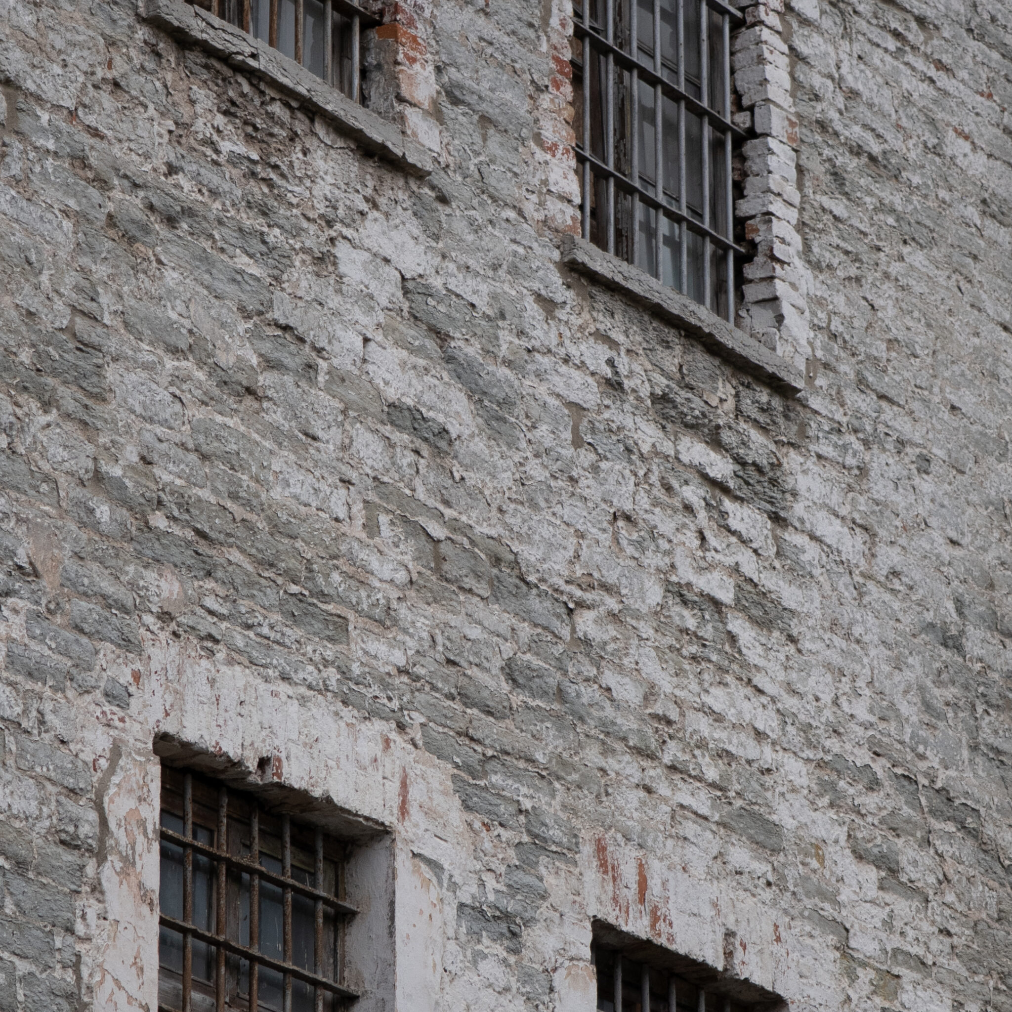 Vana ilmastikust kulunud tellishoone trellitatud akendega.