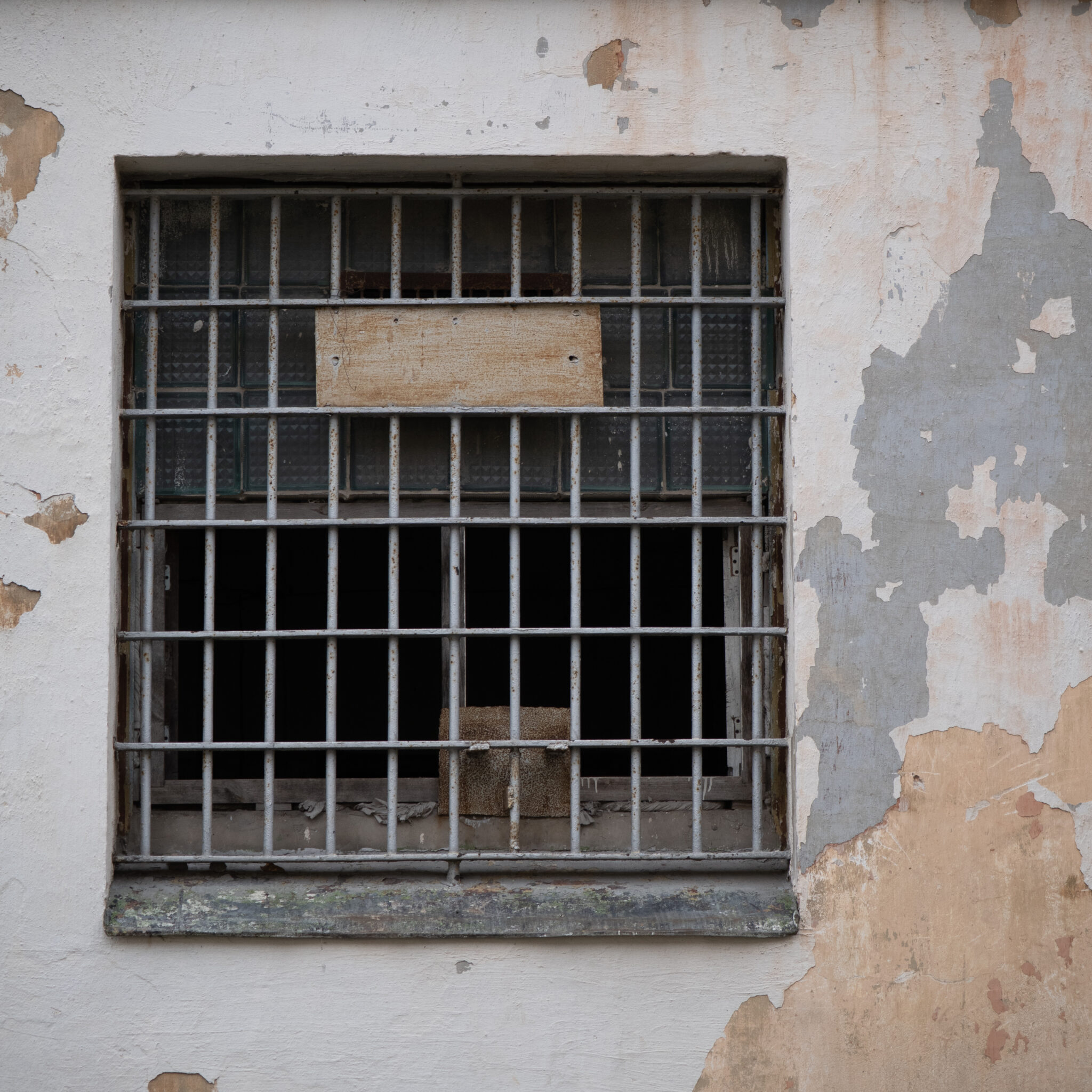 Vana trellitatud aken kooruva värviga seinal.