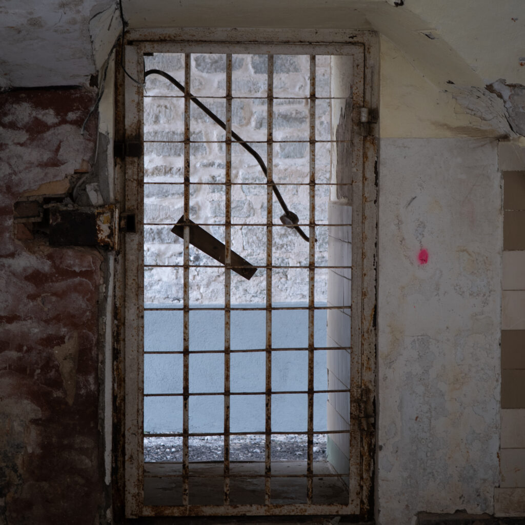 Vana roostes värav punase märgiga seinal.