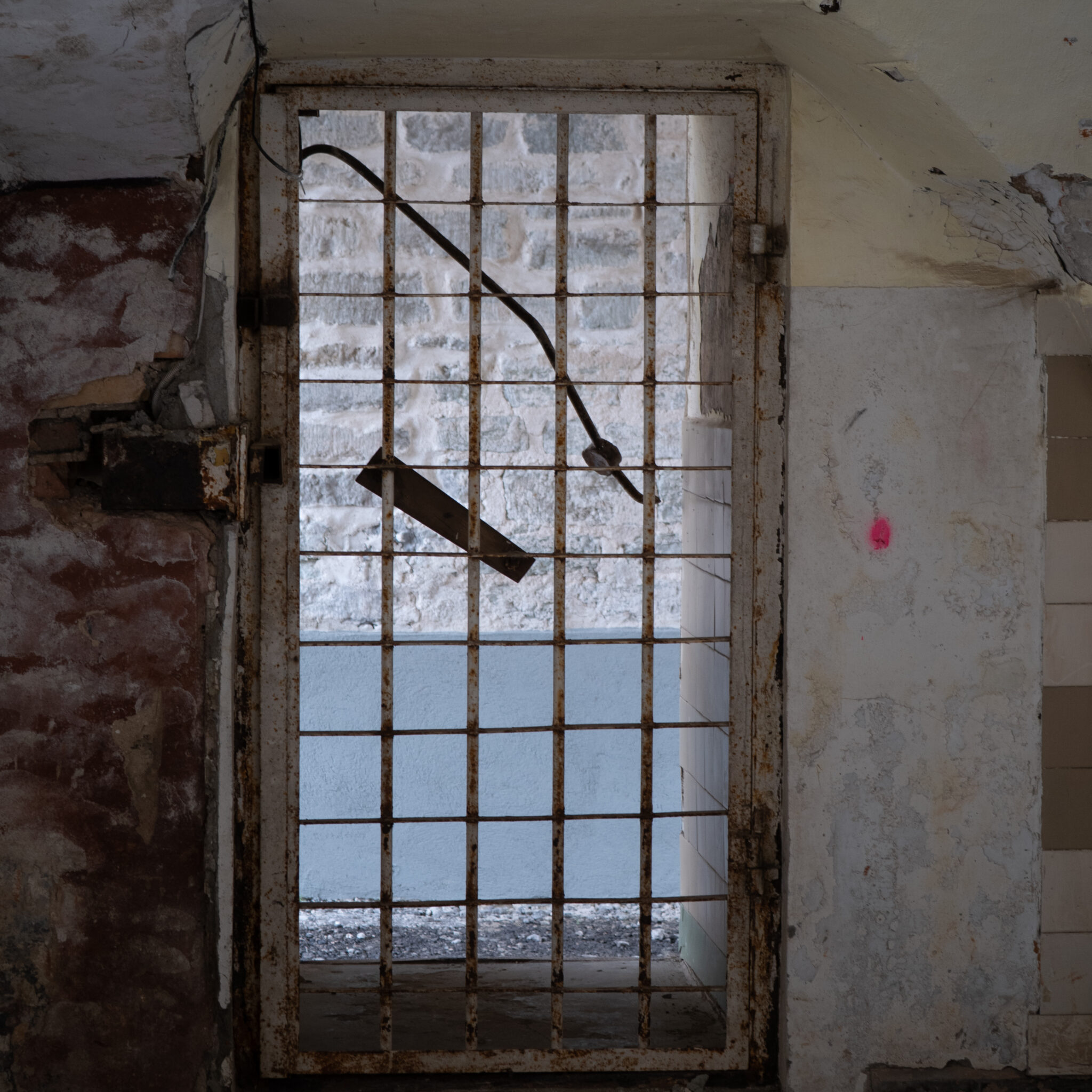 Vana roostes värav punase märgiga seinal.