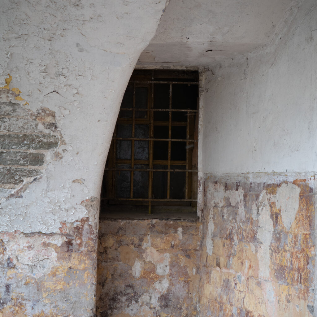 Vana kooruva värviga sein ja trellitatud aken.