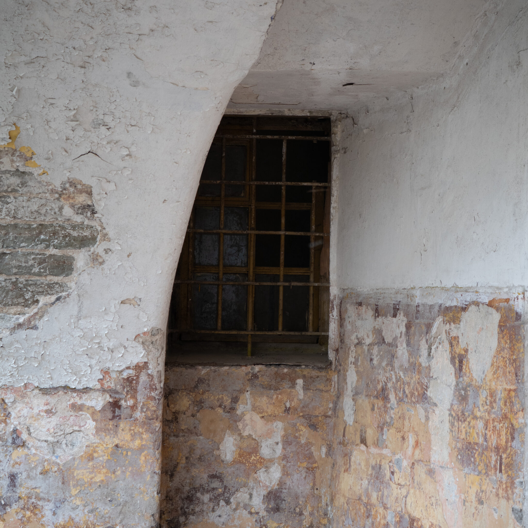 Vana kooruva värviga sein ja trellitatud aken.