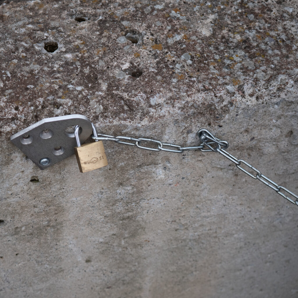 Tabalukk ja kett kinnitatud metallplaadile betoonpinnal.