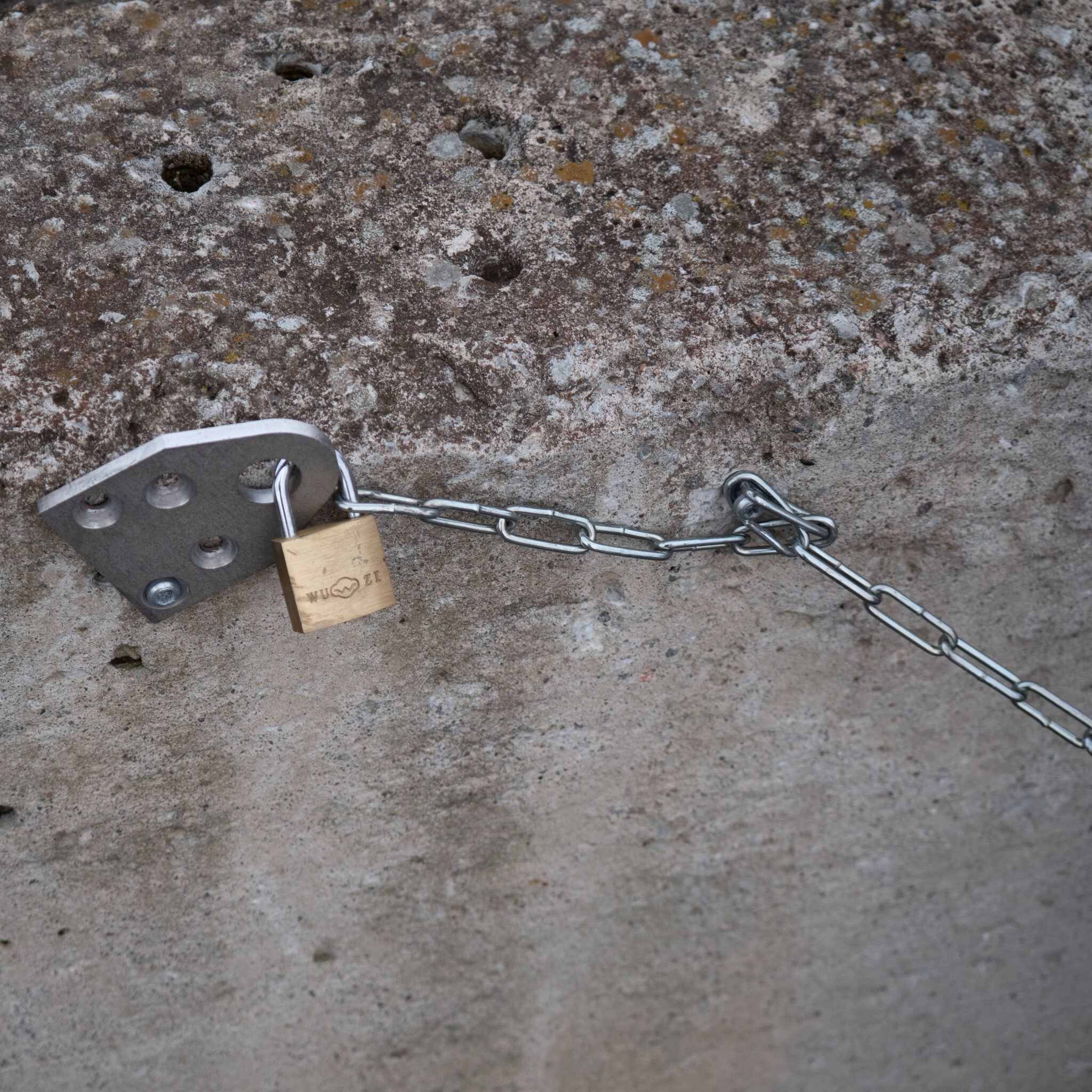 Tabalukk ja kett kinnitatud metallplaadile betoonpinnal.