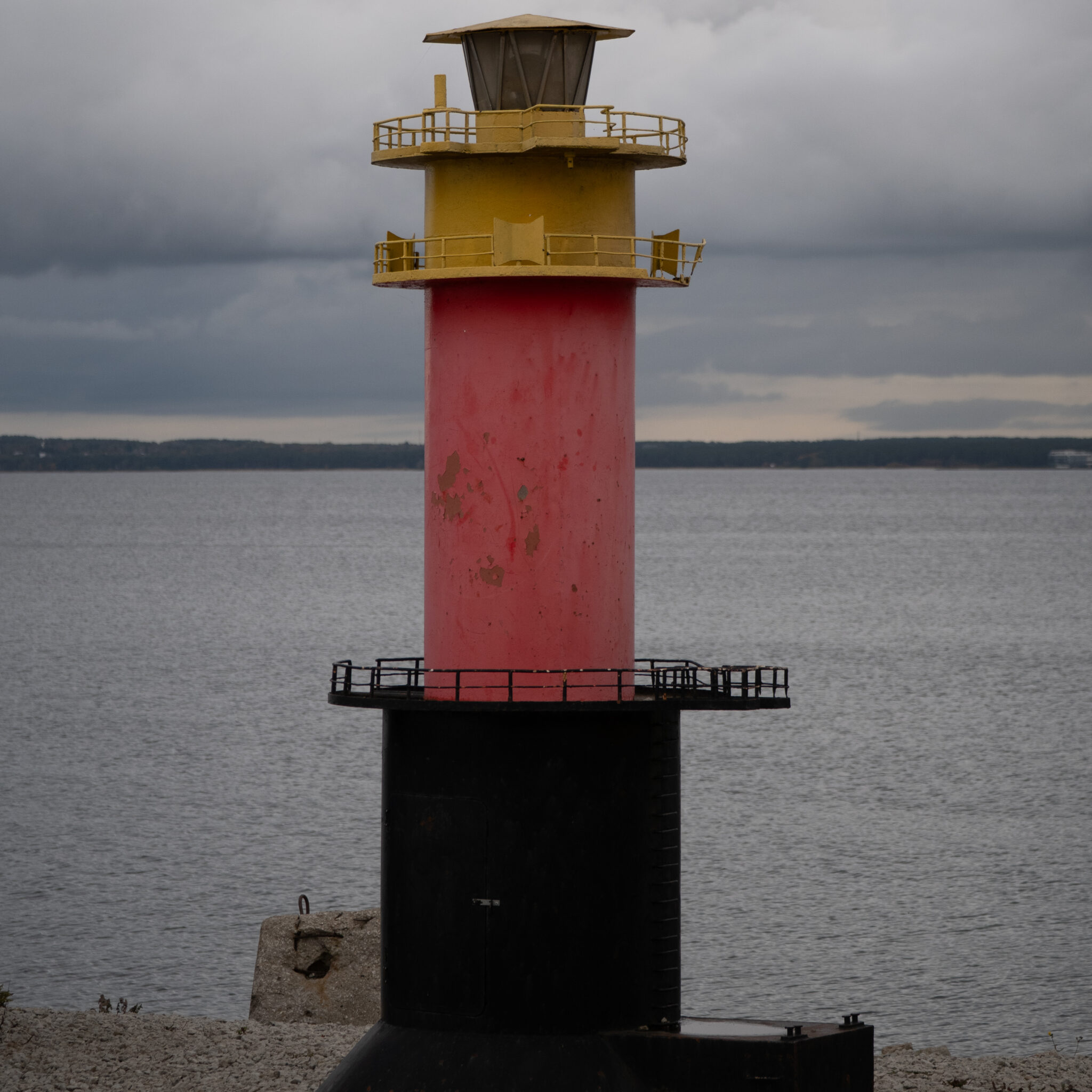 Punane ja kollane tuletorn kivisel rannikul.