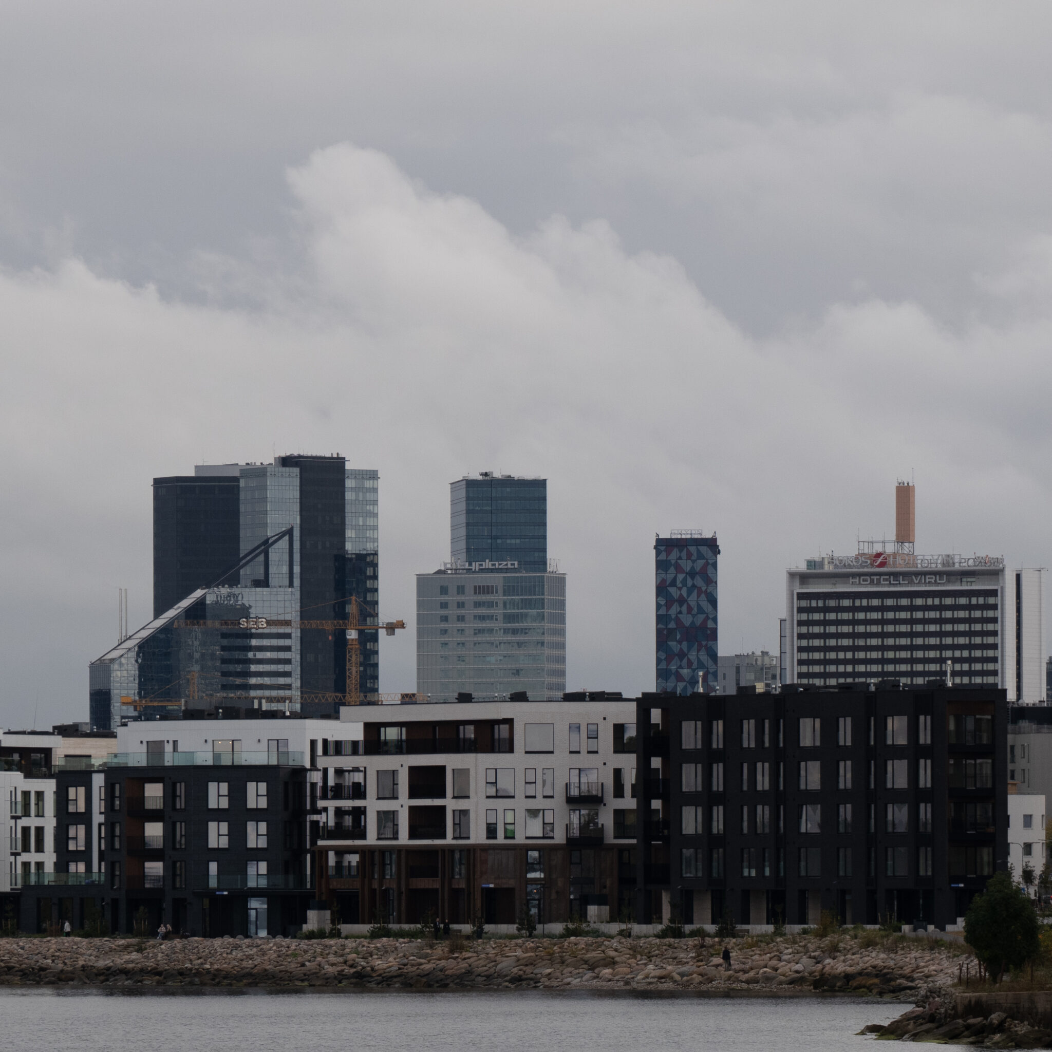 Kaasaegne linnasiluett pilvede ja veega esiplaanil.