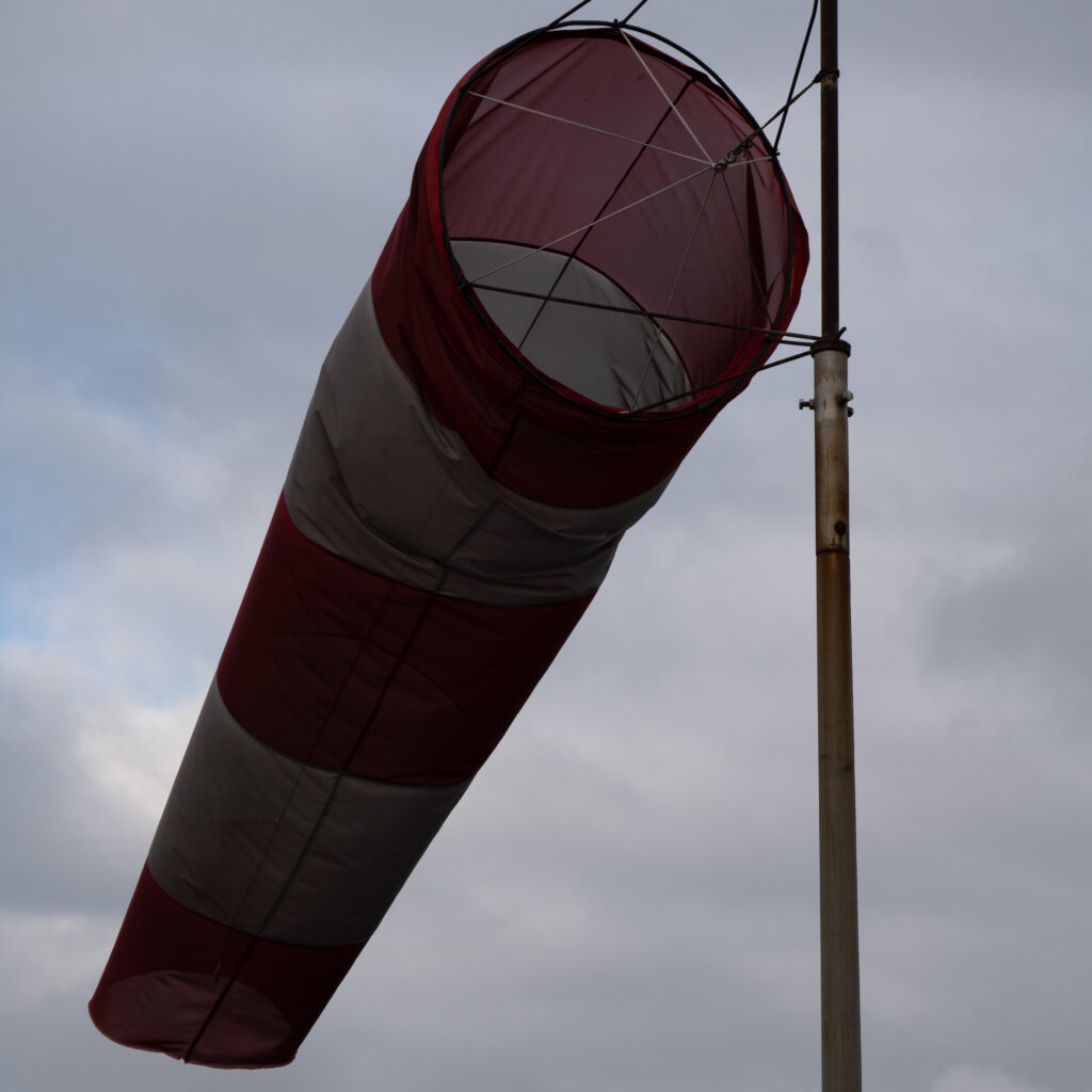 Punase-valge triibuline tuulesokk pilvise taeva taustal.