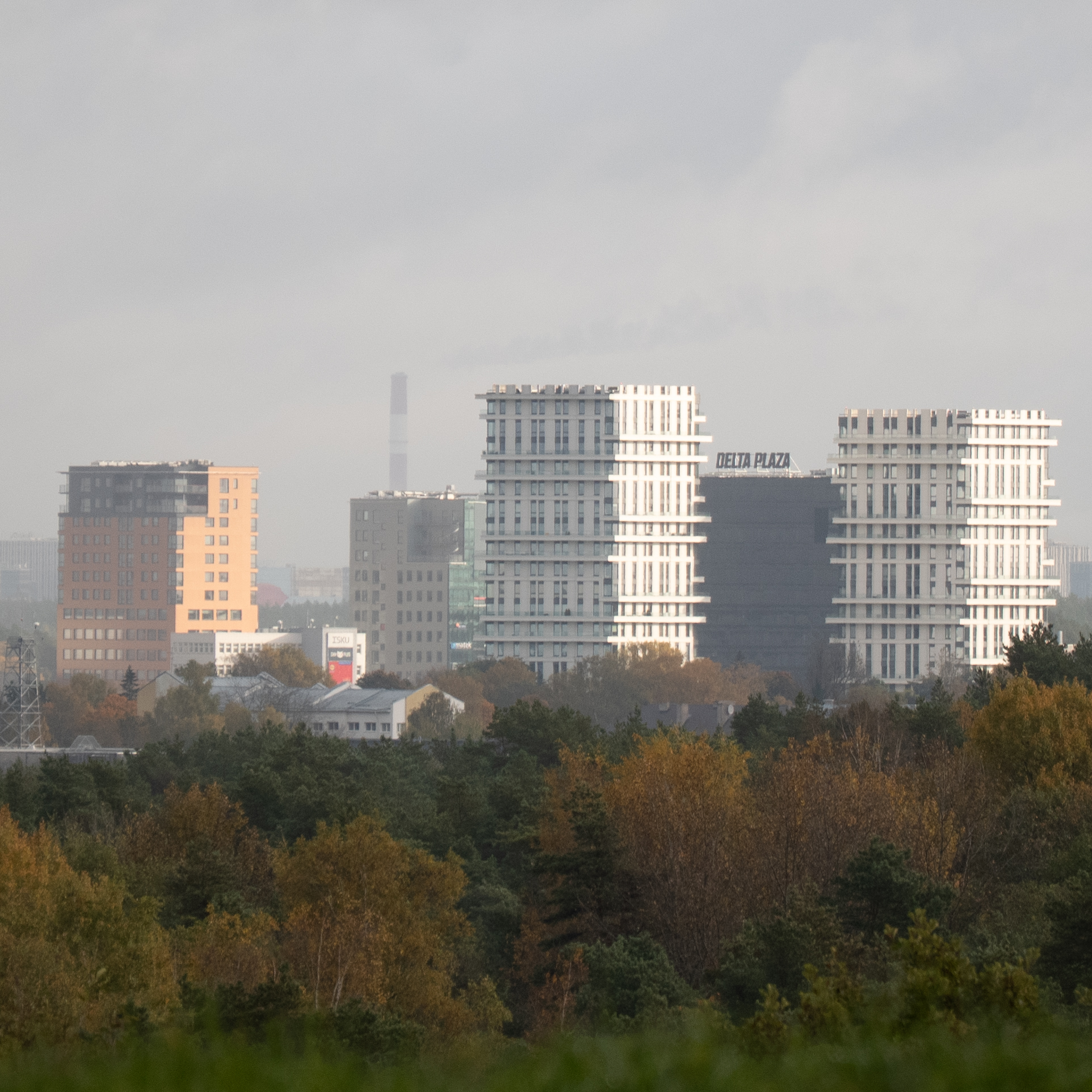 Kaasaegsed hooned ja puud pilvise taeva taustal.