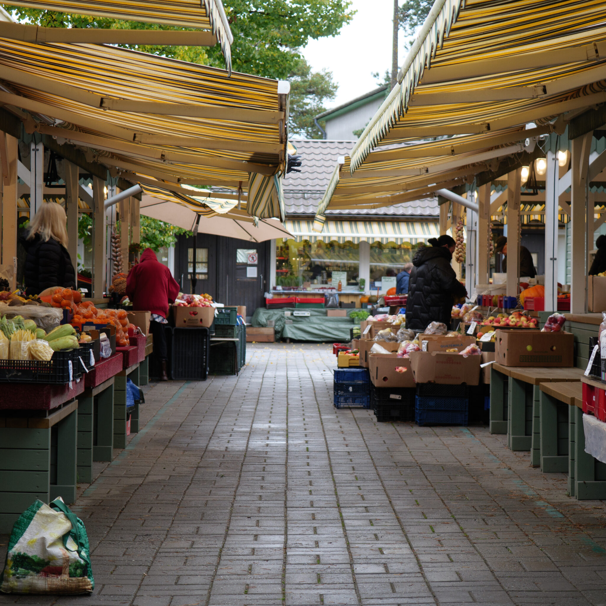Turg puu- ja köögiviljalettidega triibuliste varikatuste all.