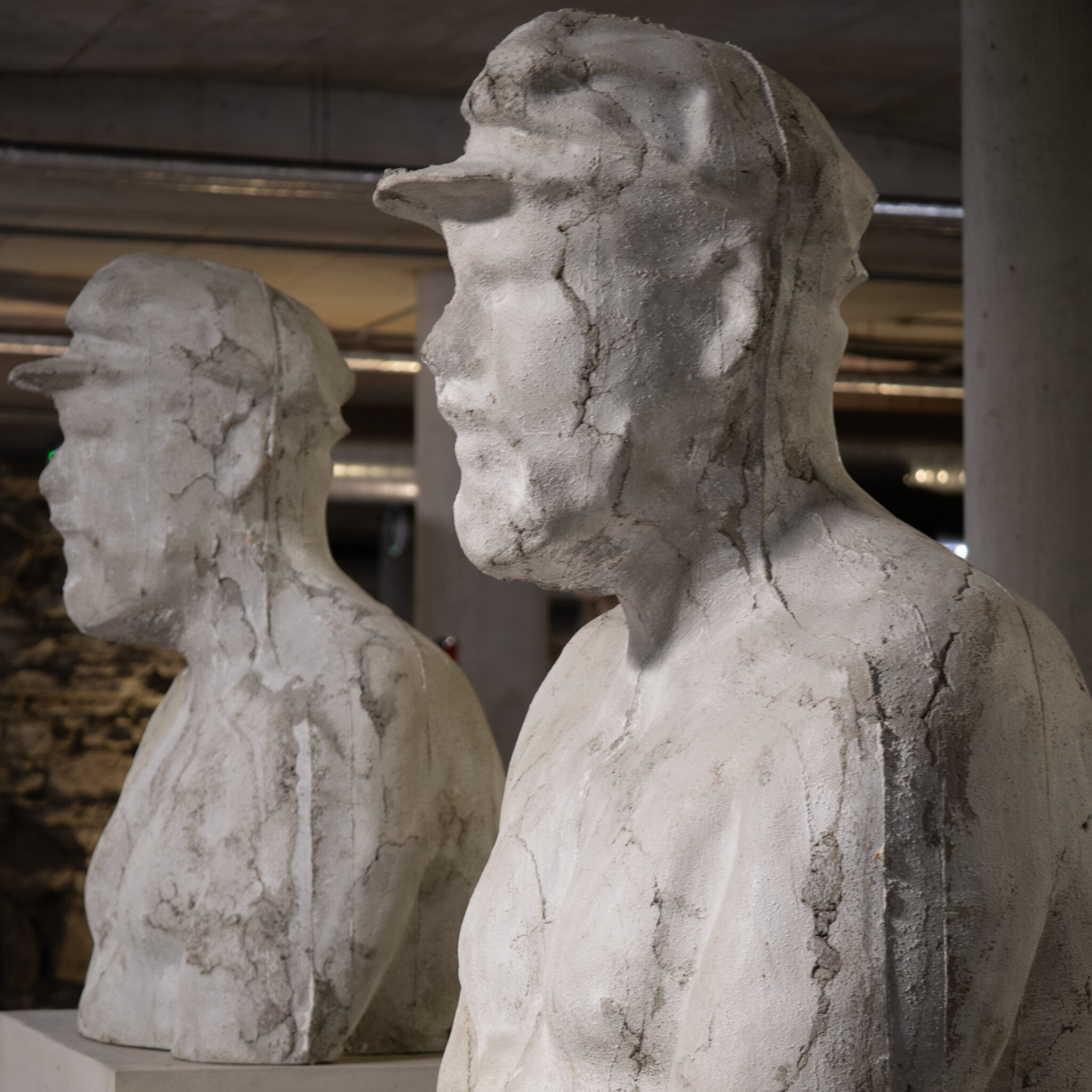 Kaks betoonskulptuuri mütsidega meestest.