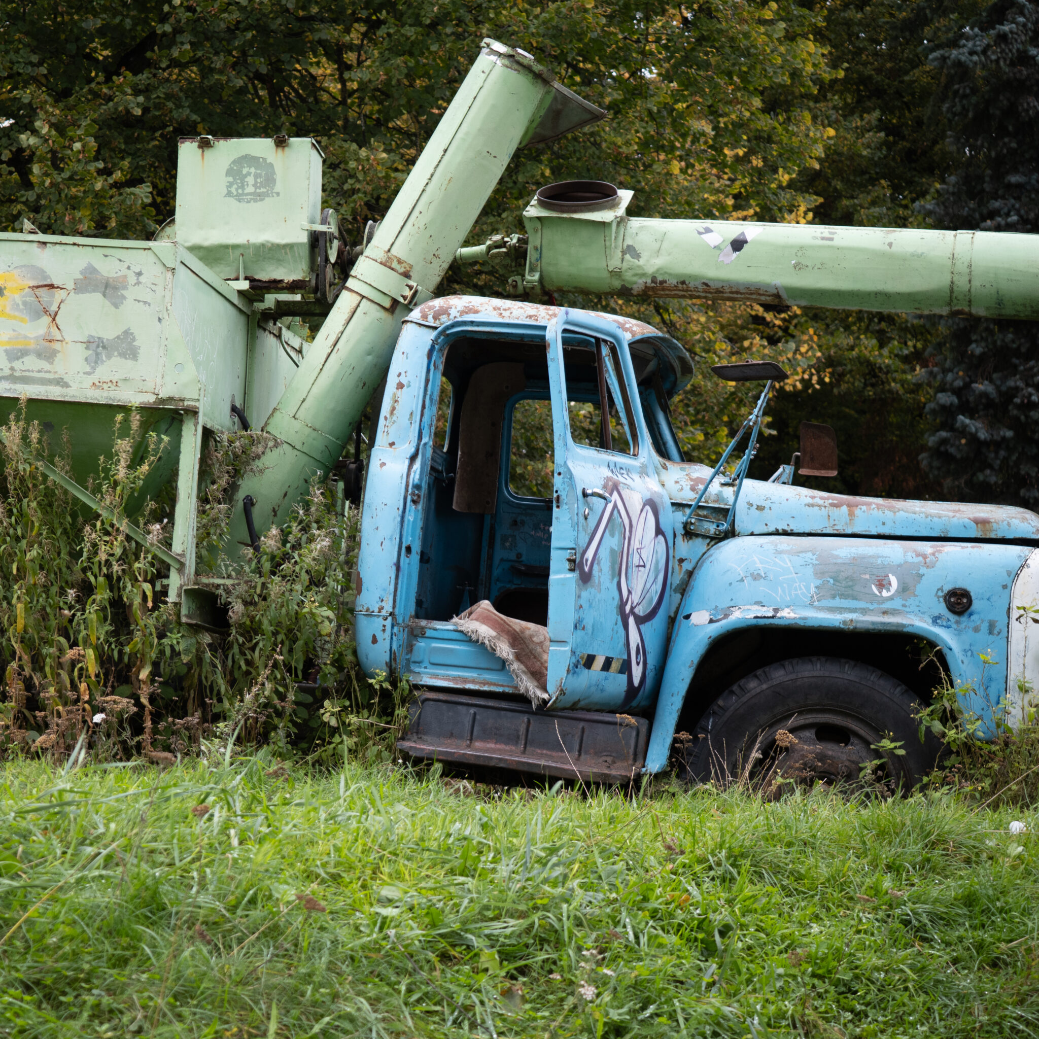 Vana roostes sinine veoauto graffitiga põllu peal.