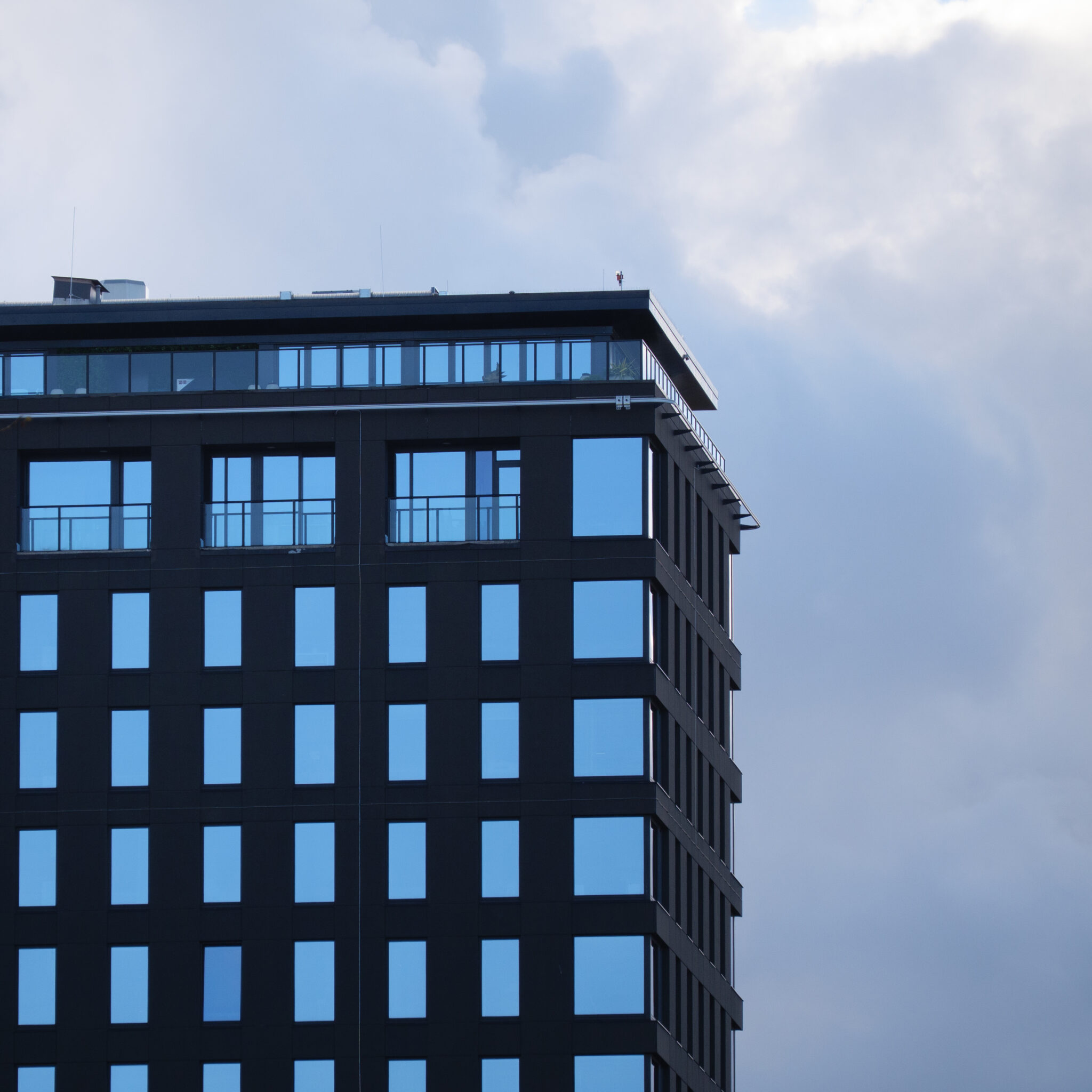 Moodne must siniste akendega pilvelõhkuja pilvise taeva all.