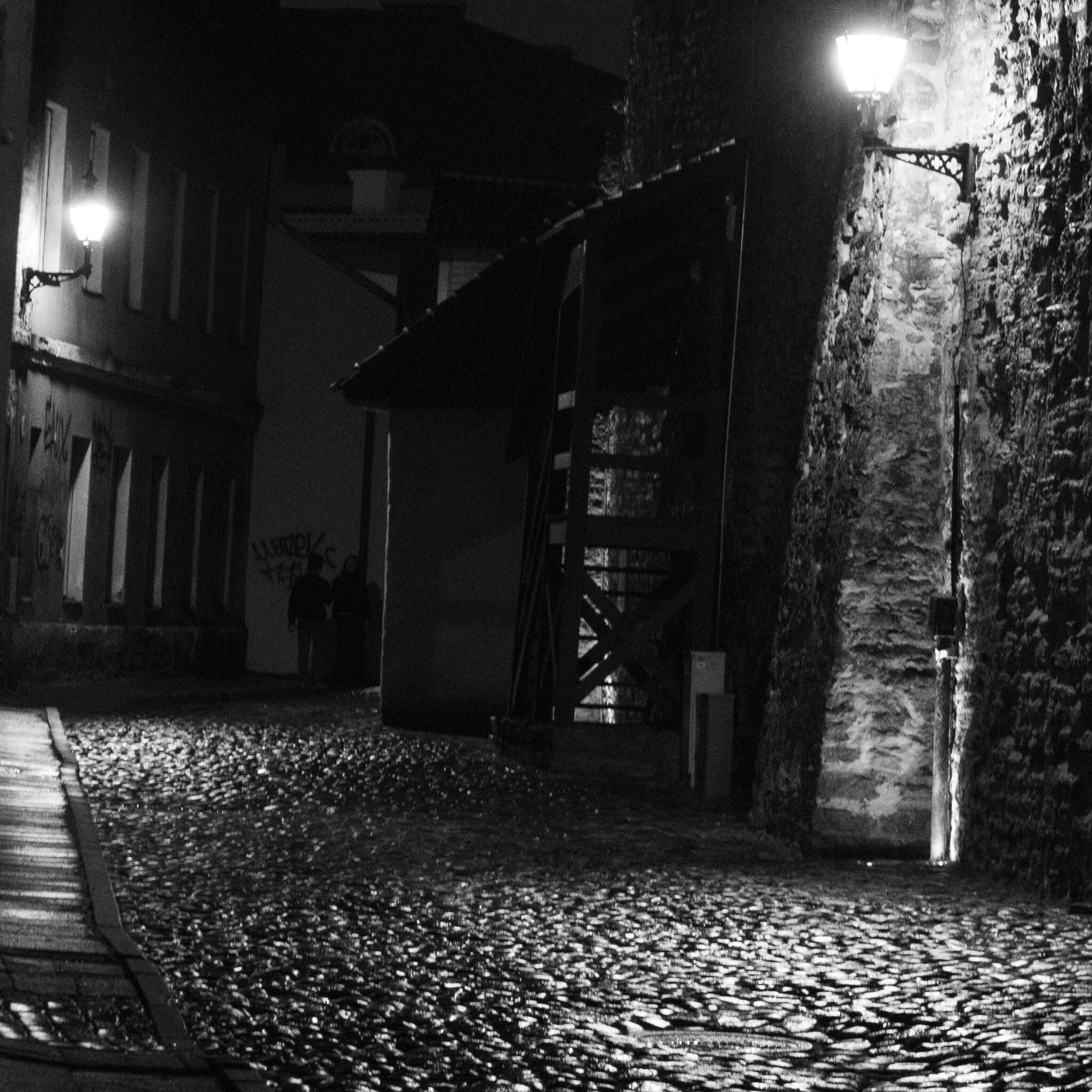 Kaks inimest seisavad hämaralt valgustatud allees.