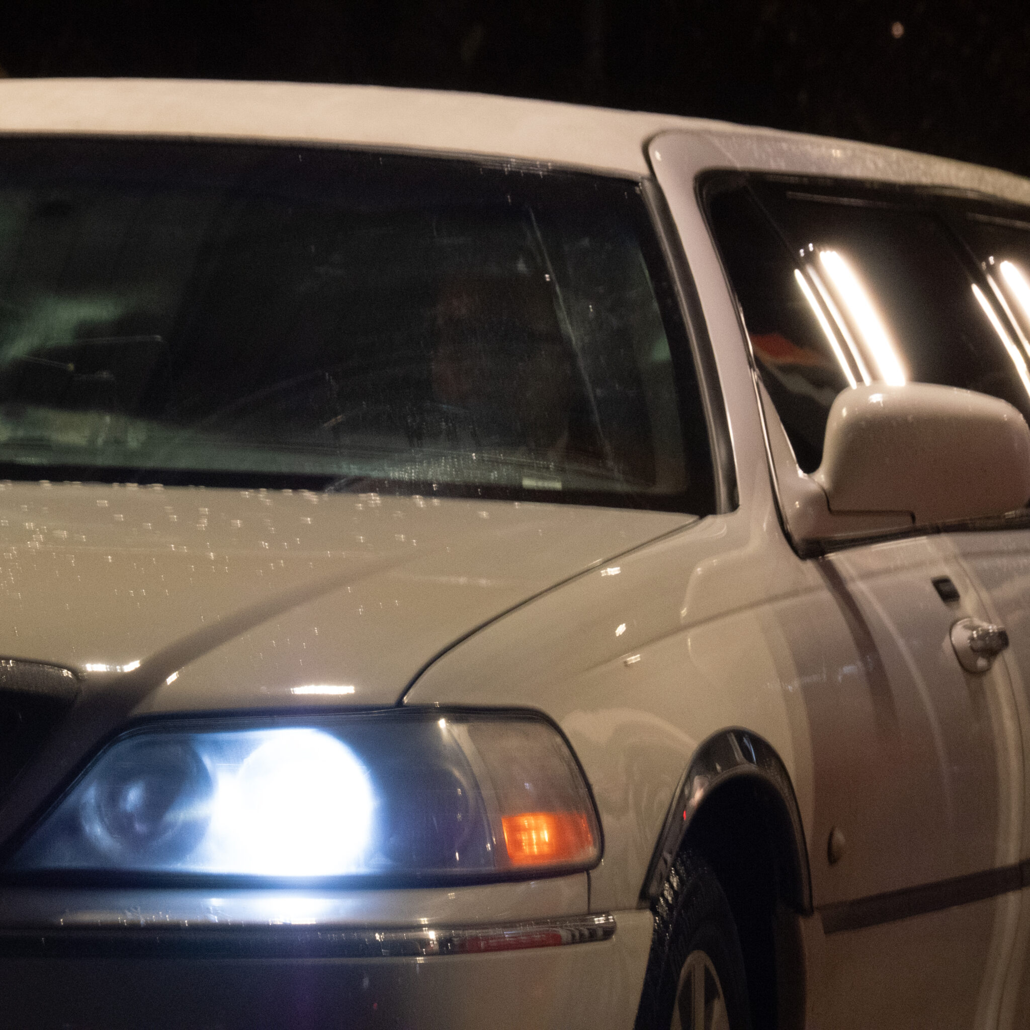 Valge limusiin öösel põlevate esituledega.