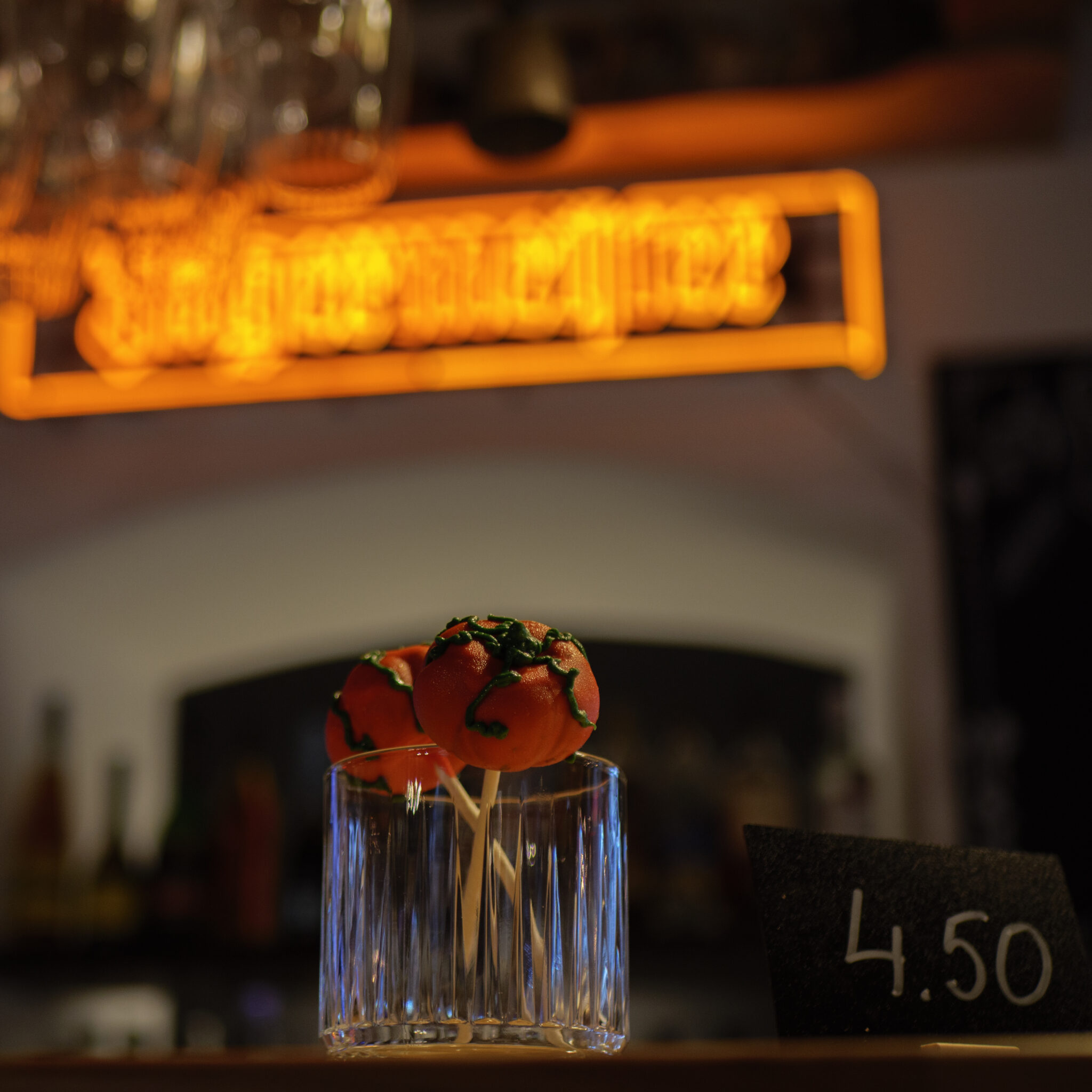 Kolm kõrvitsakujulist koogipopsi baaris klaasis.