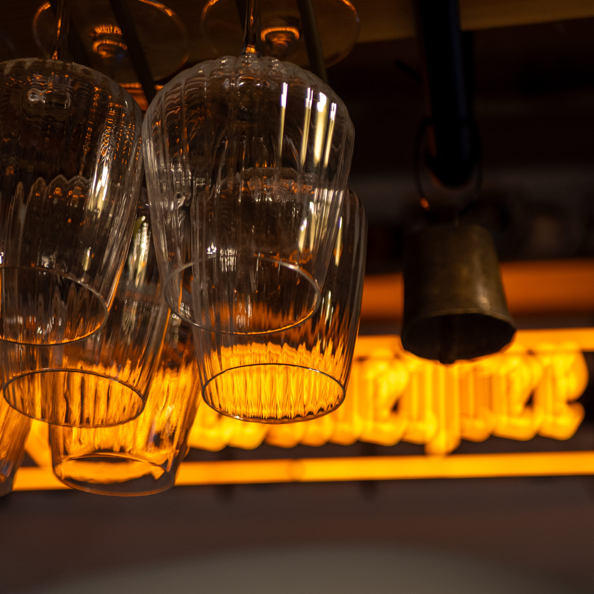 Lühtri küljes rippuvad veiniklaasid, taustal neoonsilt.