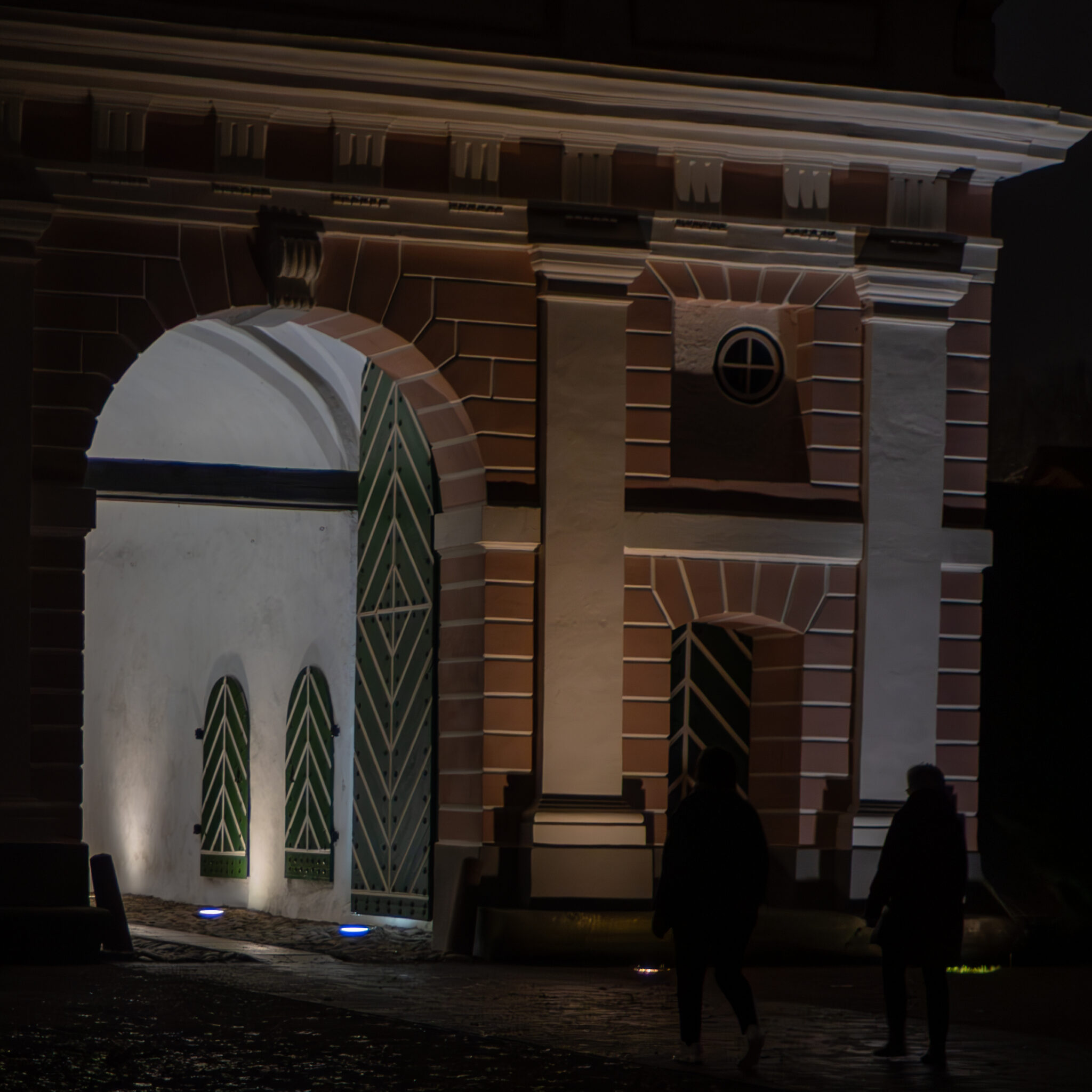 Kaks inimest kõnnivad öösel ajaloolise hoone juures.