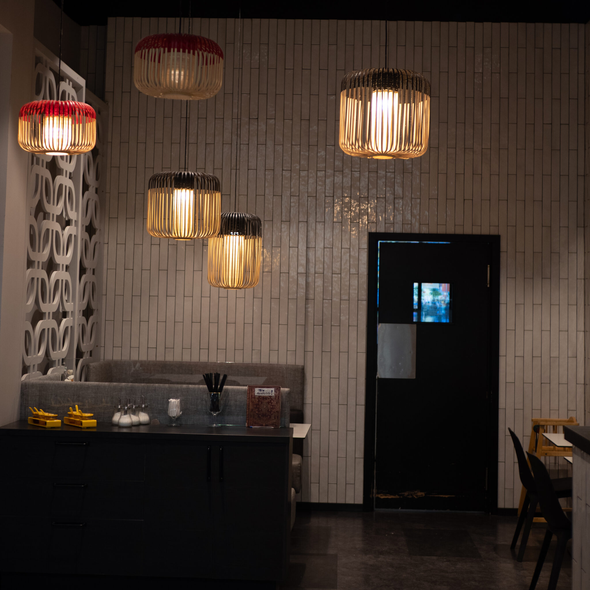 Kolm rippuvat valgustit valgustavad musta uksega restorani.