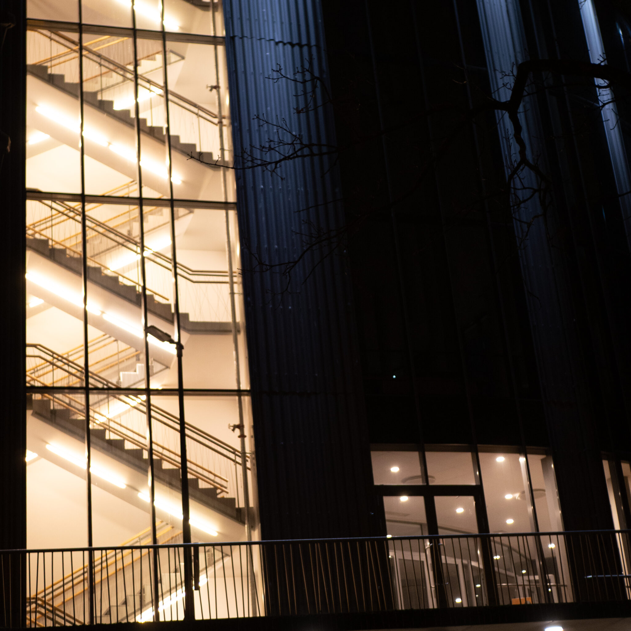 Moodne klaasfassaadiga hoone ja valgustatud trepid öösel.