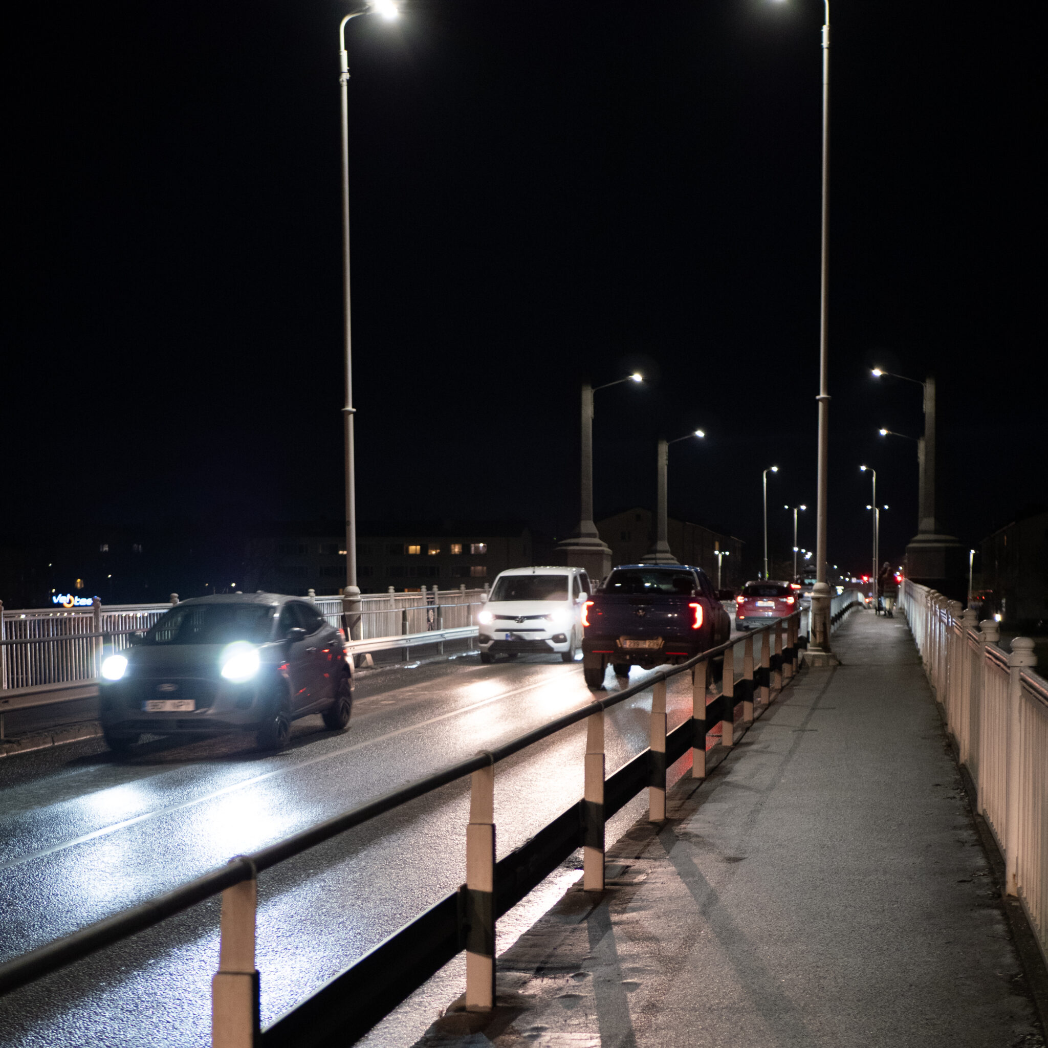 Autod sillal öösel tänavavalgustite, piirde ja hoonetega.