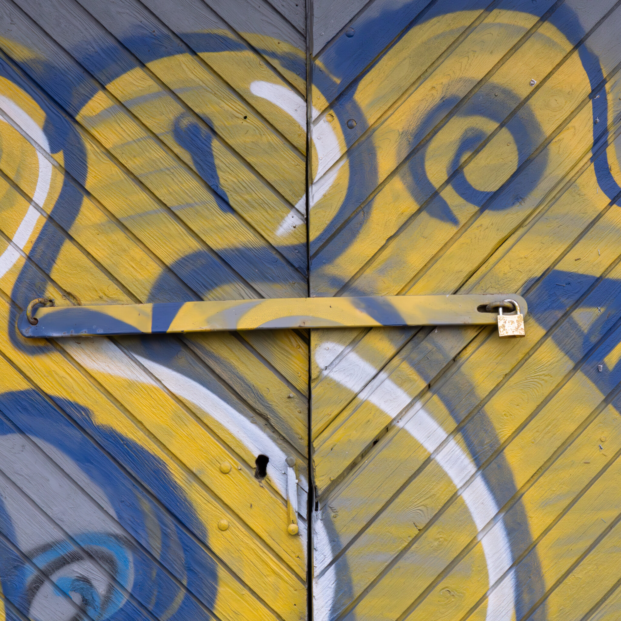 Kollane ja sinine tabaluku ning graffitiga uks.