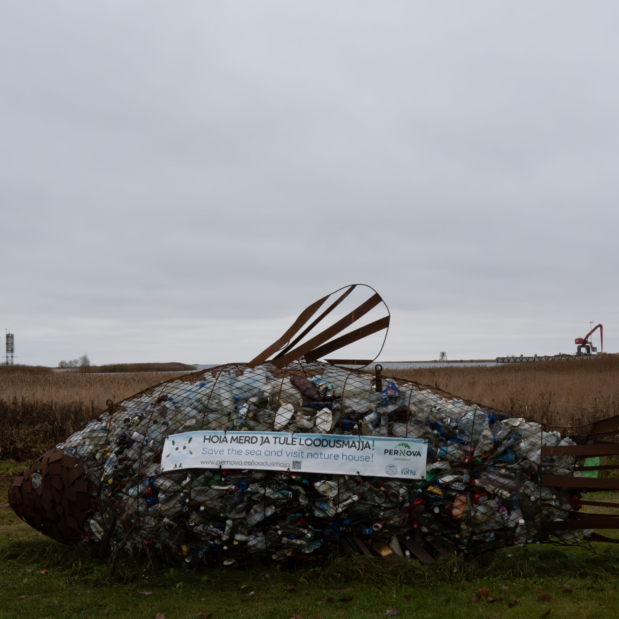 Plastpudelitest tehtud suur kalaskulptuur looduskaitsele kutsuva sildiga.