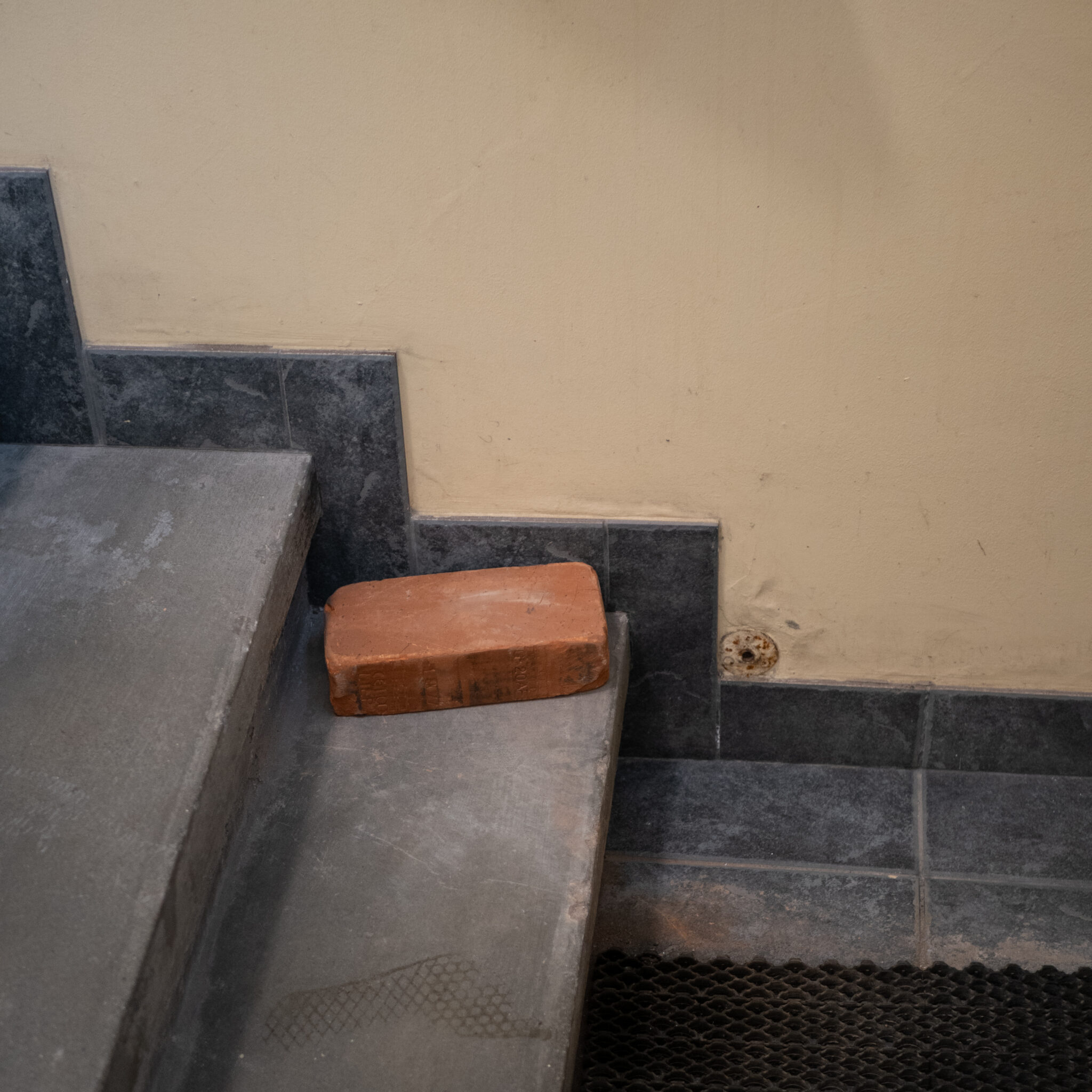 Punane telliskivi lebab betoonserva peal tumedate plaatide kohal.