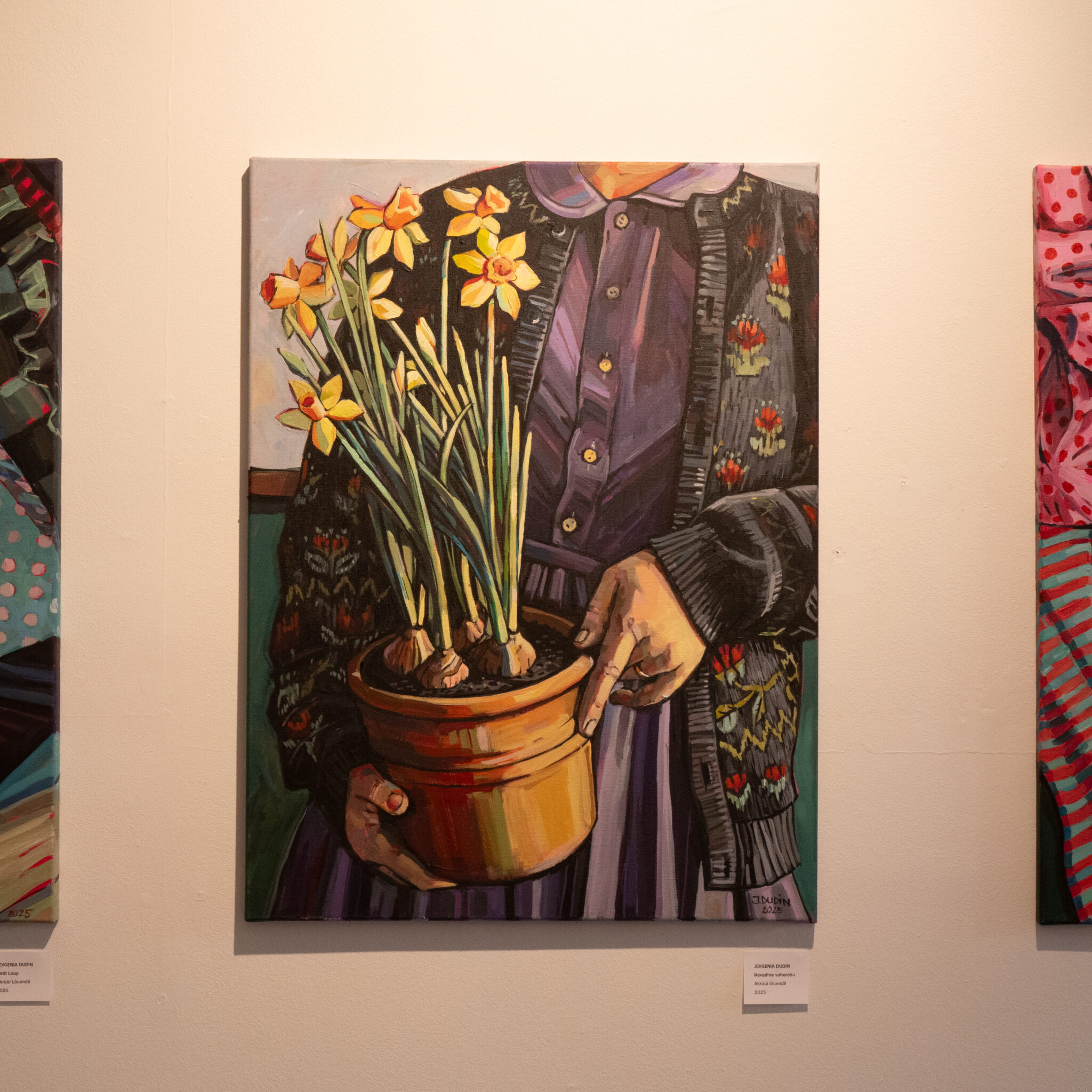 Maal inimesest, kes hoiab nartsissidega lillepotti.