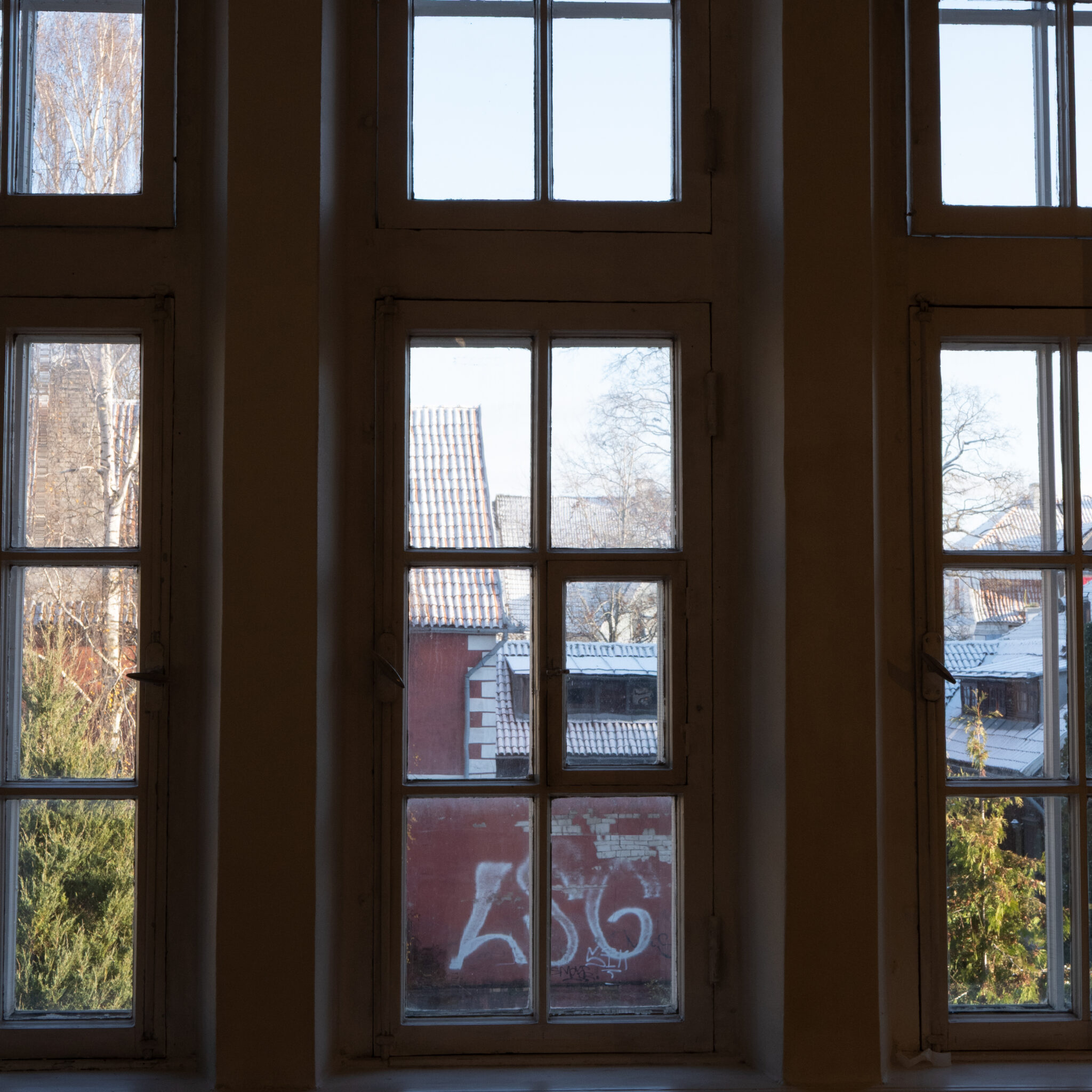 Rida aknaid vaatega punasele hoonele ja kivikatustele.