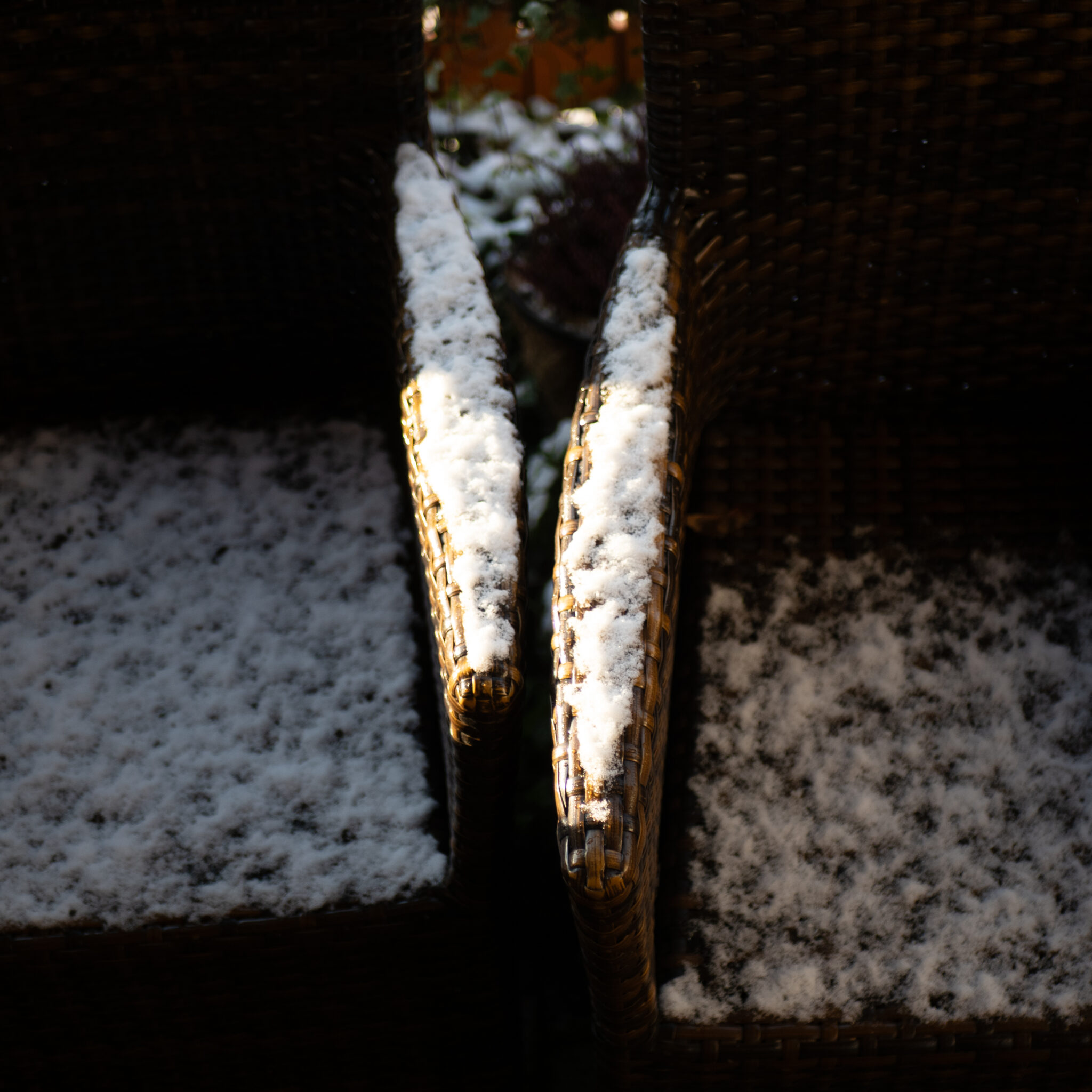 Päikesevalguses lumega kaetud punutud toolid.