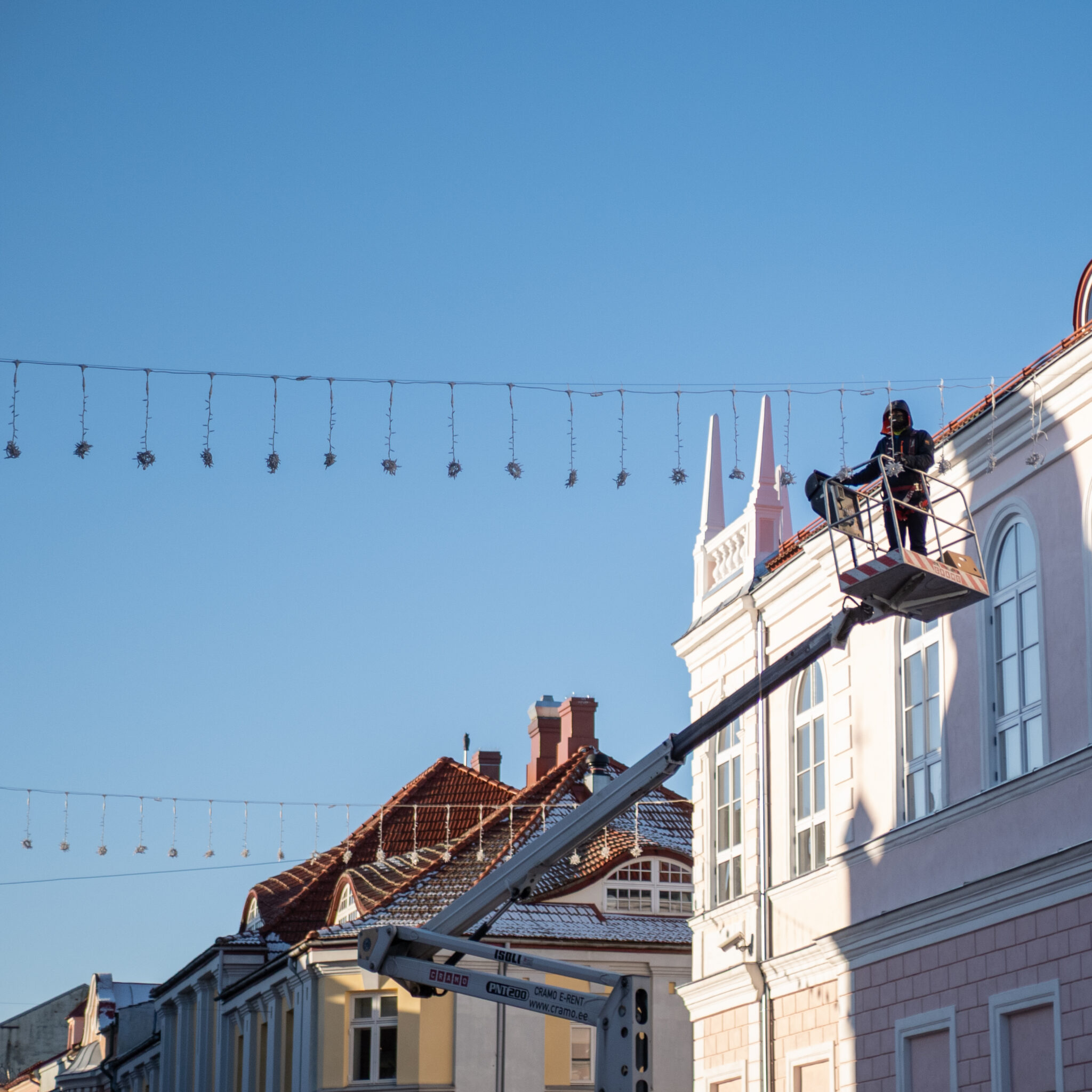 Tööline tõstukil hoone kohal jõulutulede juures.