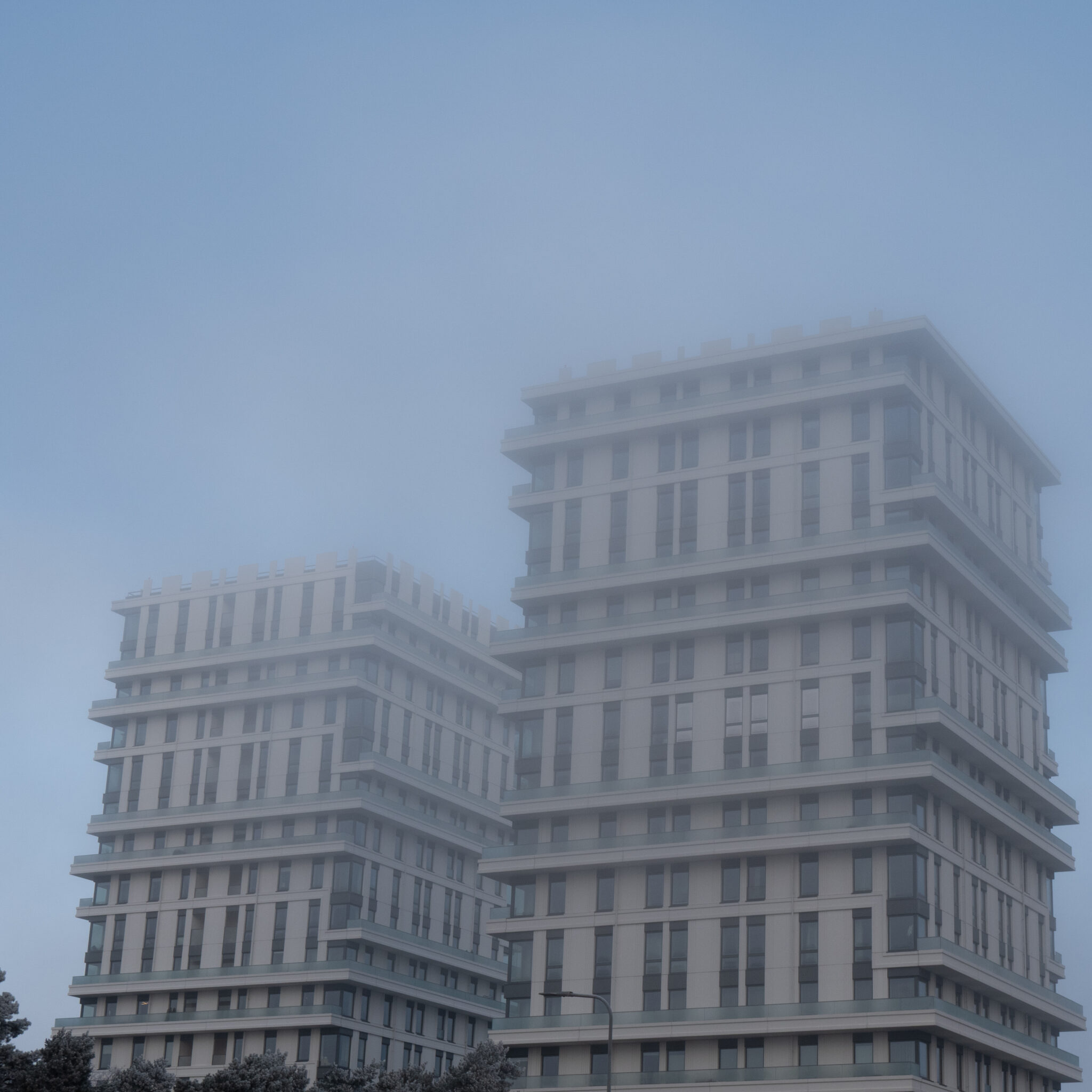 Kaks modernset pilvelõhkujat tõusevad udu kohale.