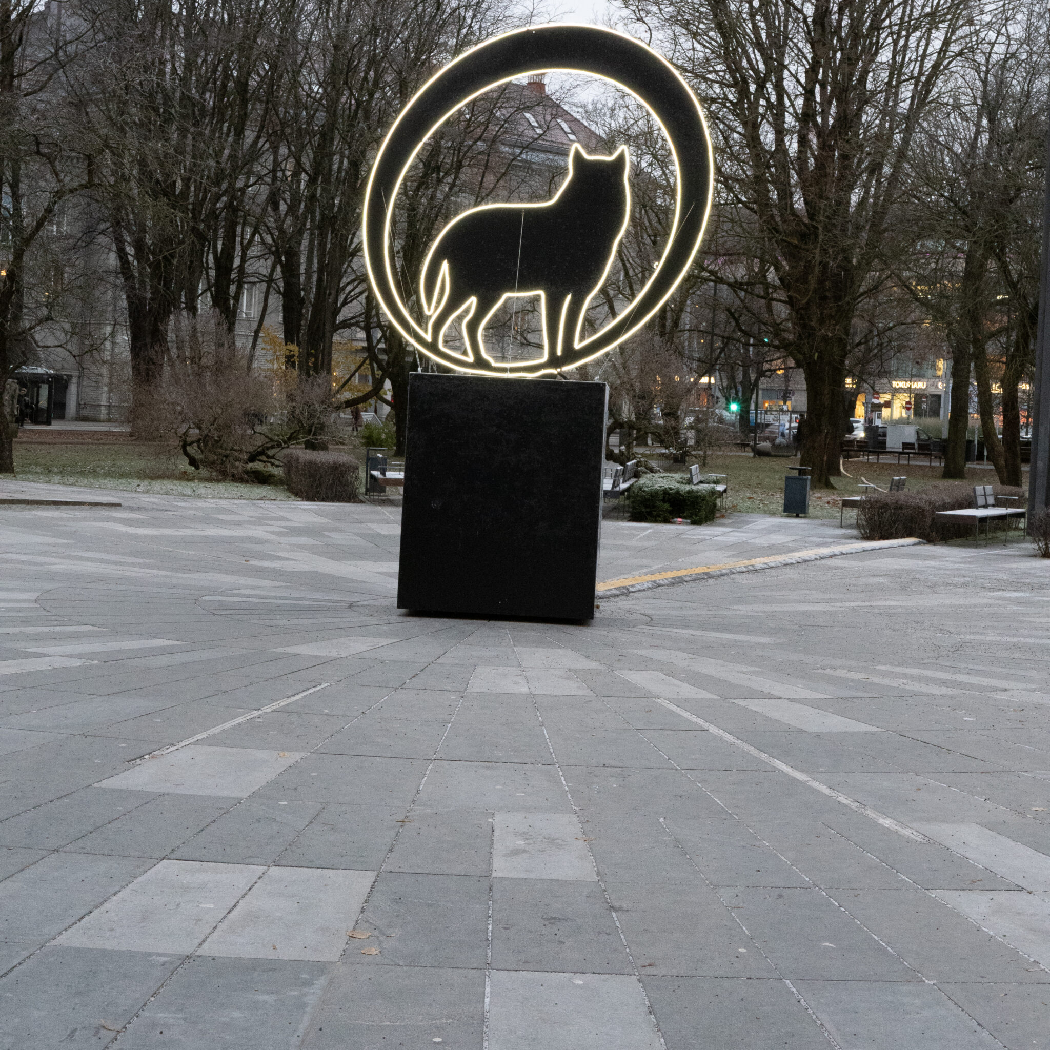 Helendav kassiskulptuur kiviparketiga väljakul.