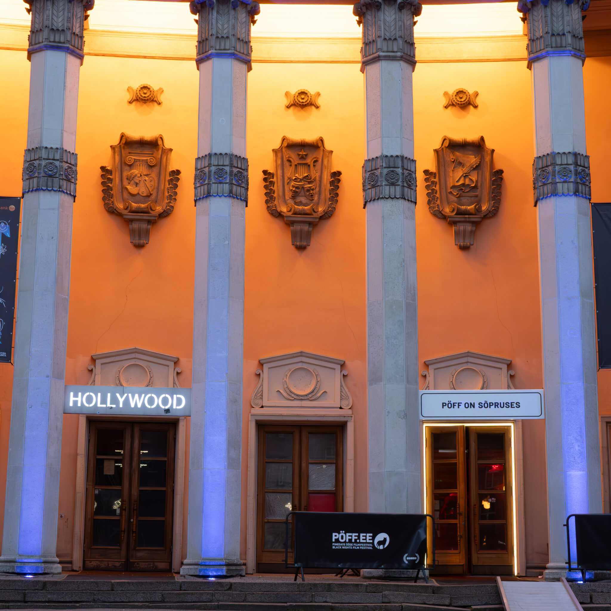 Sammaste ja valgustatud sissepääsudega hoone Hollywoodi ja PÖFFi sissekäikudega.