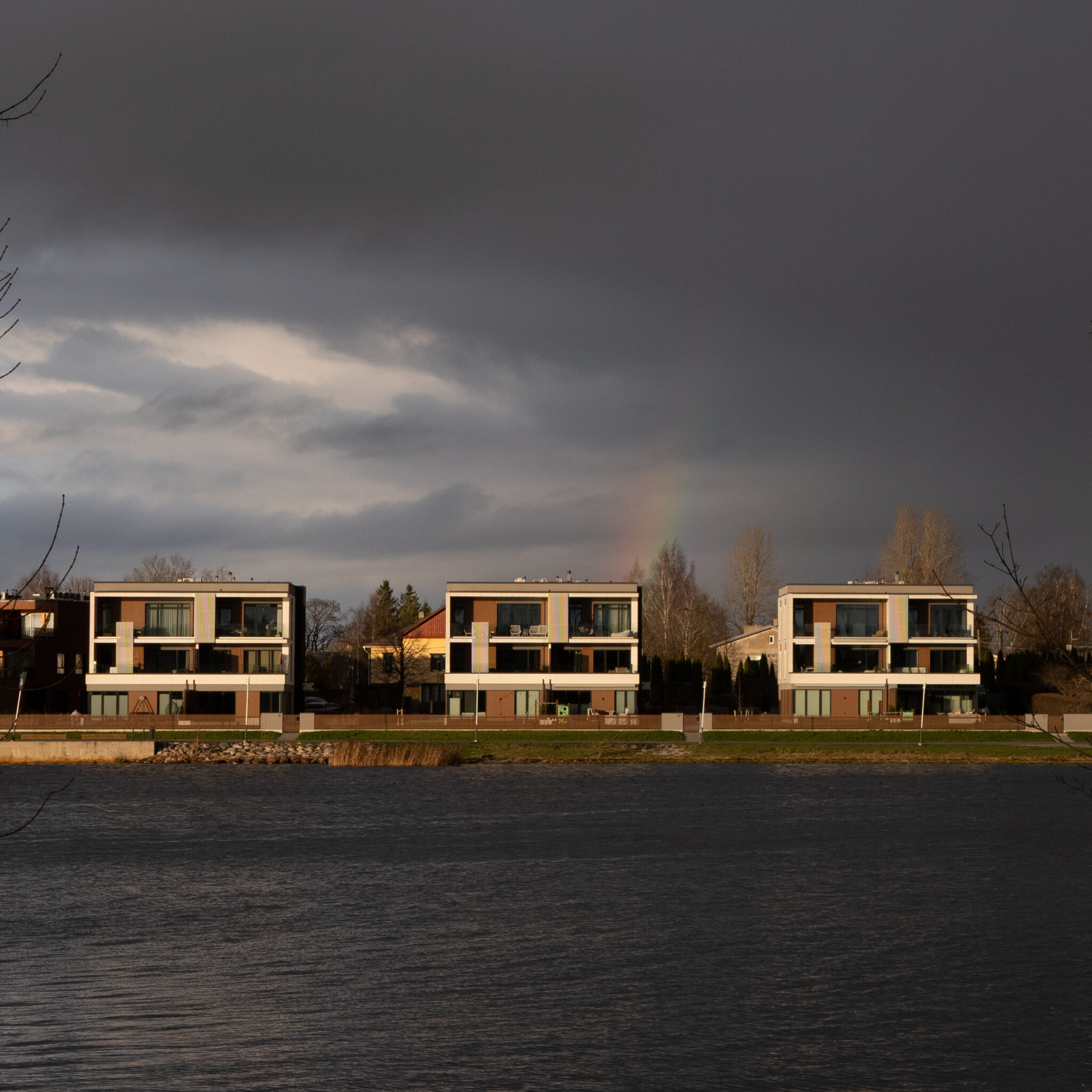 Kaasaegsed kortermajad järve ääres, taevas vikerkaar.