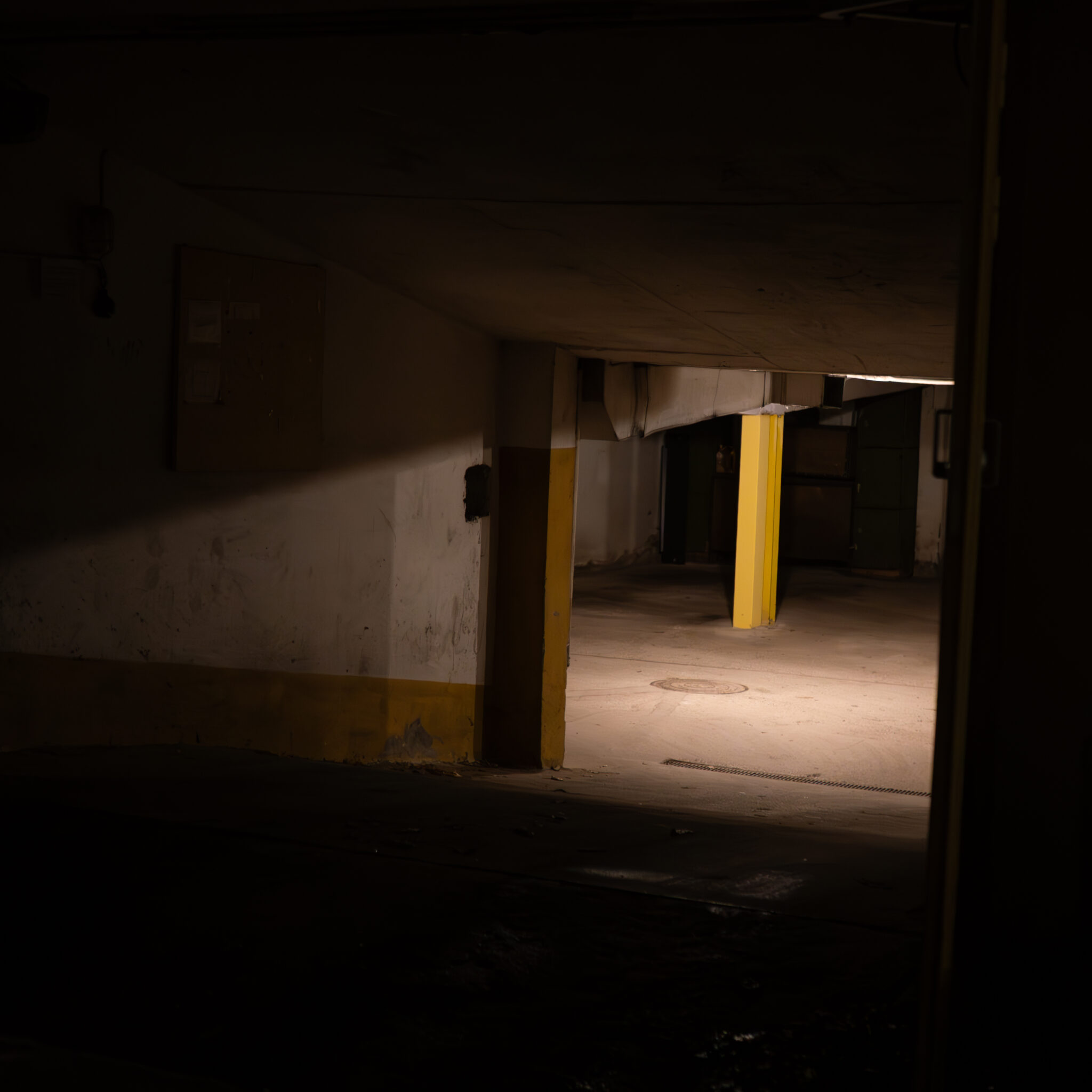 Hämar tööstuslik koridor kollaste sammastega.