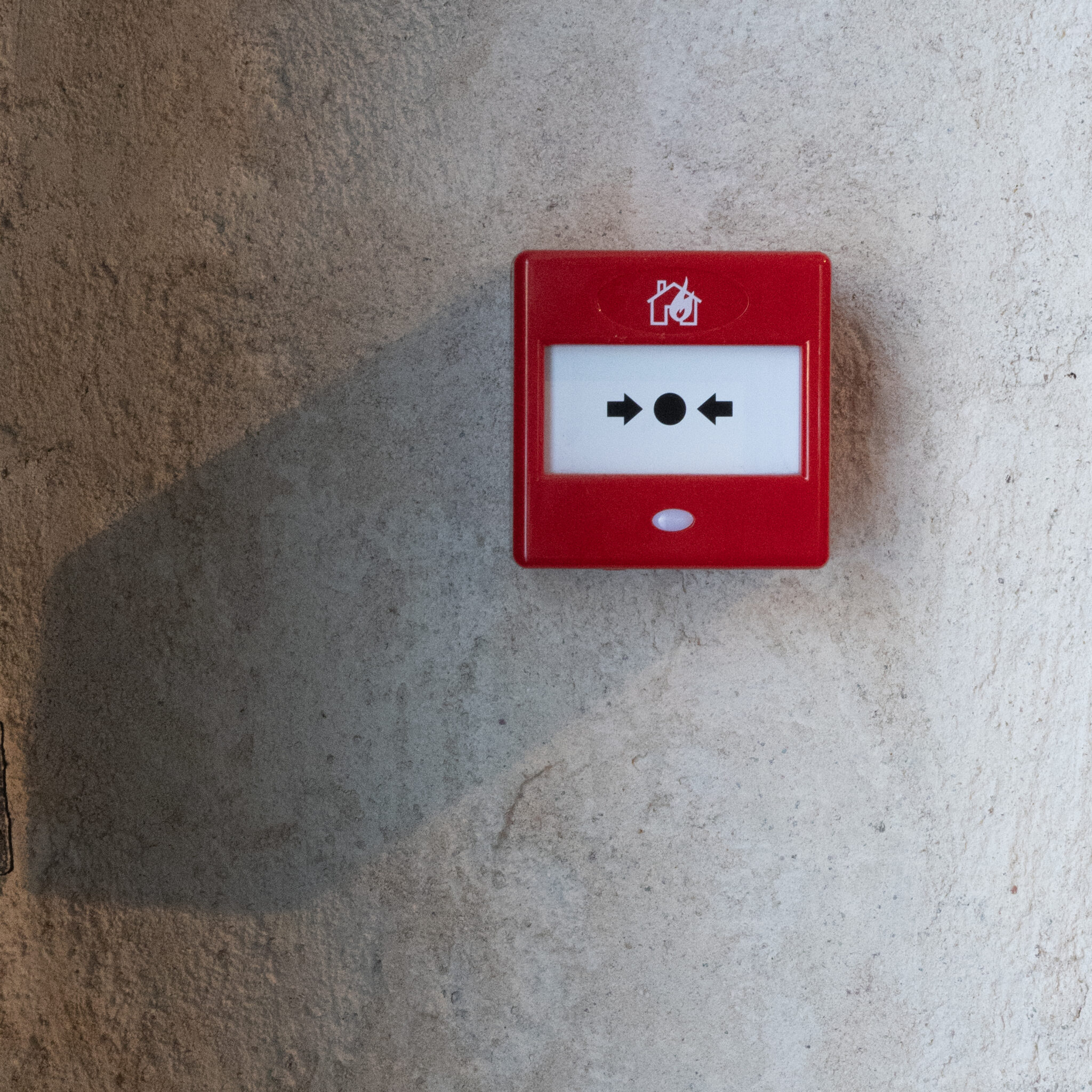 Punane tulekahjuhäirenupp betoonseinal.