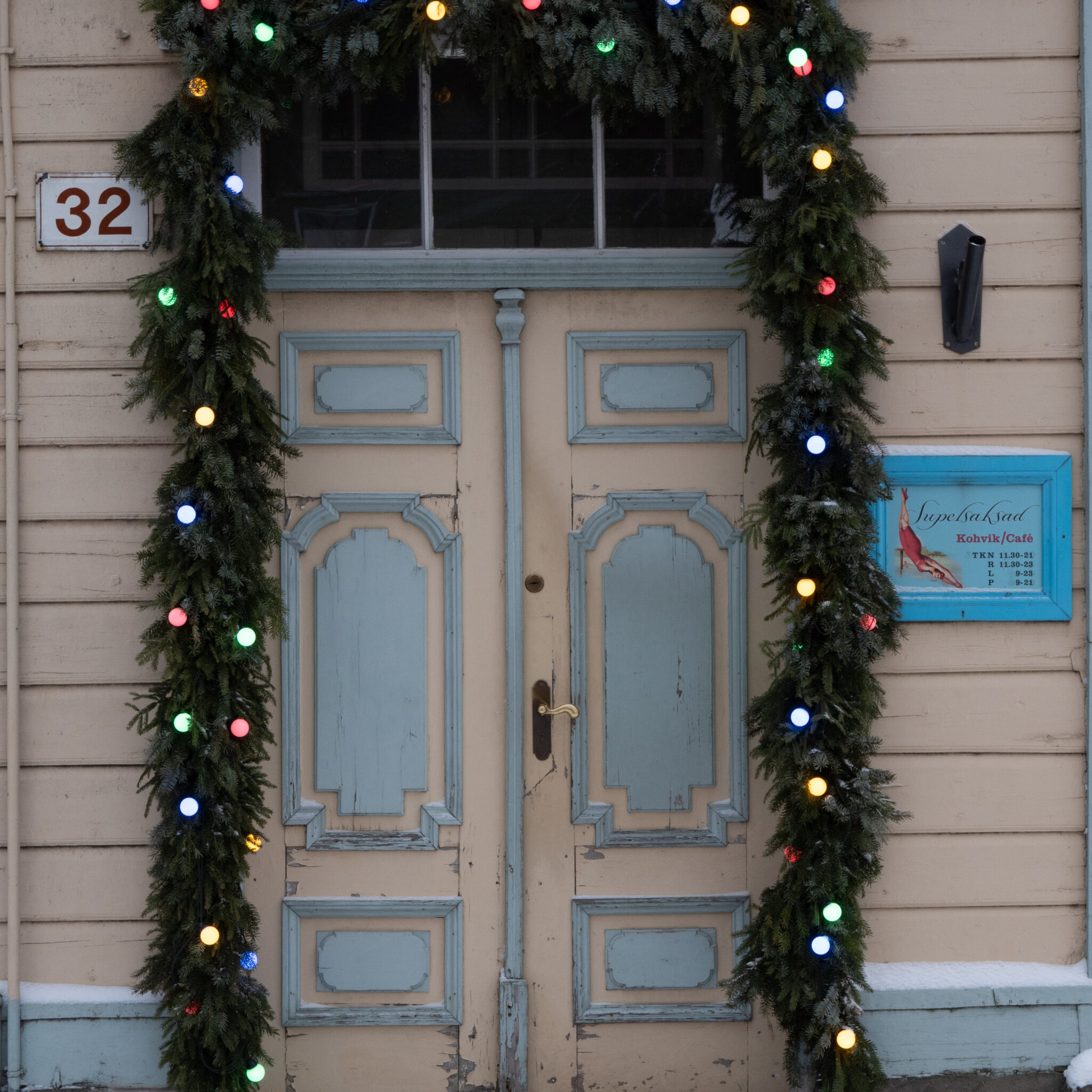 Jõulutuled kaunistavad sinise raamiga ust numbriga 32.