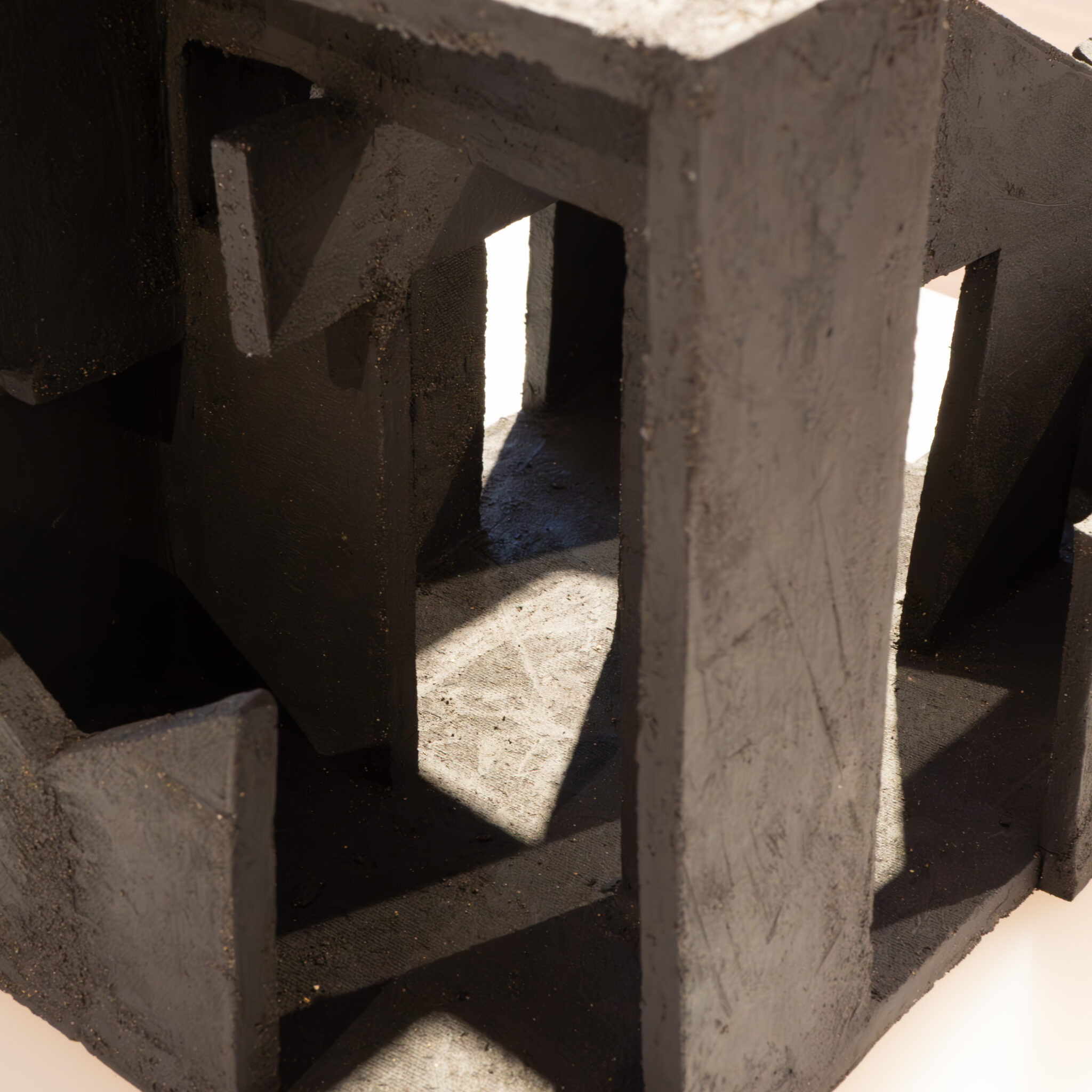 Must geomeetriline skulptuur, mille vahedest paistab valgus.